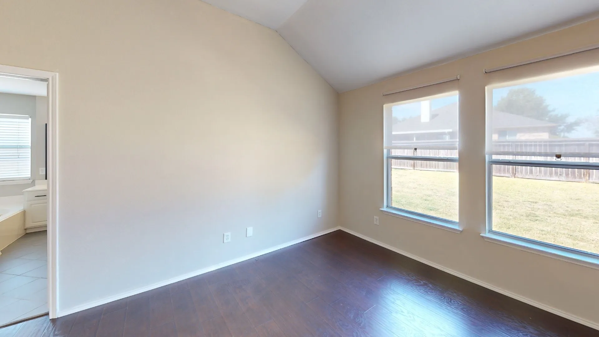 Vaulted ceilings, wood-finish flooring, and double windows with roller shades