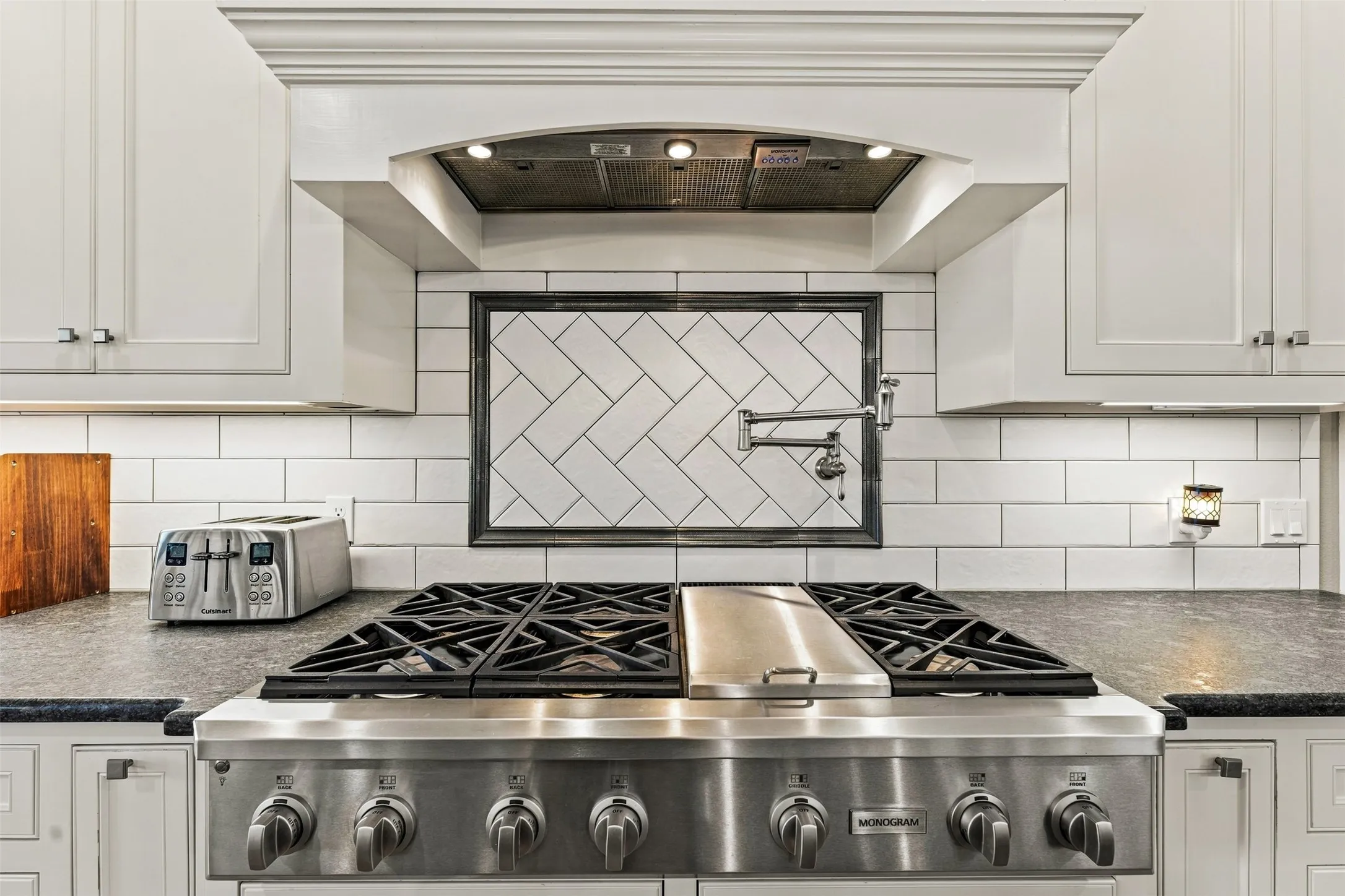 The kitchen features a stainless steel six-burner gas range with integrated griddle and convenient pot filler.