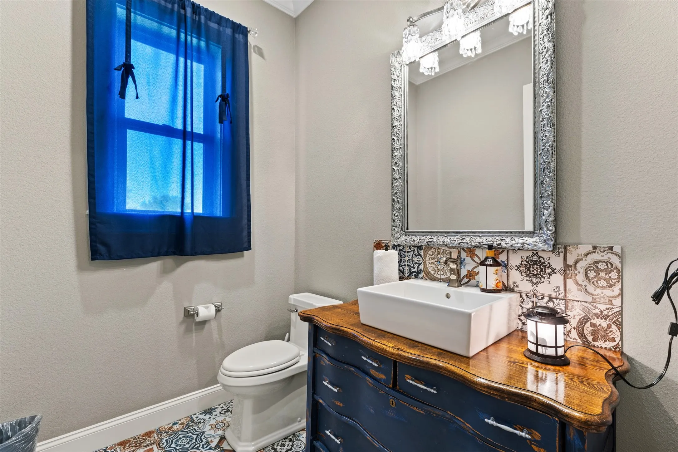 The half bathroom located in the hallway has a colorful and vibrant tile floor and backsplash.
