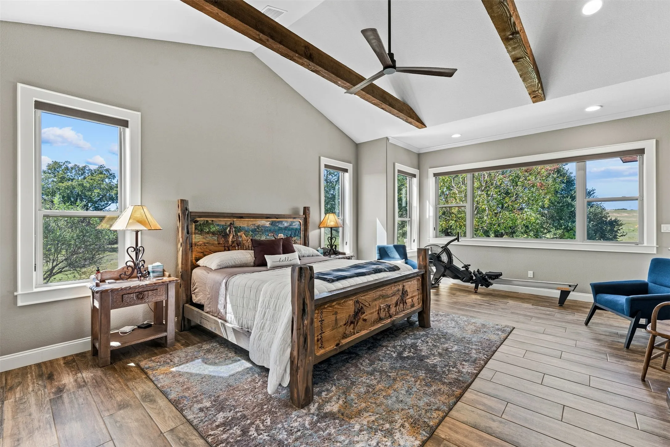 The primary bedroom boasts a vaulted ceiling, beams, and large windows.