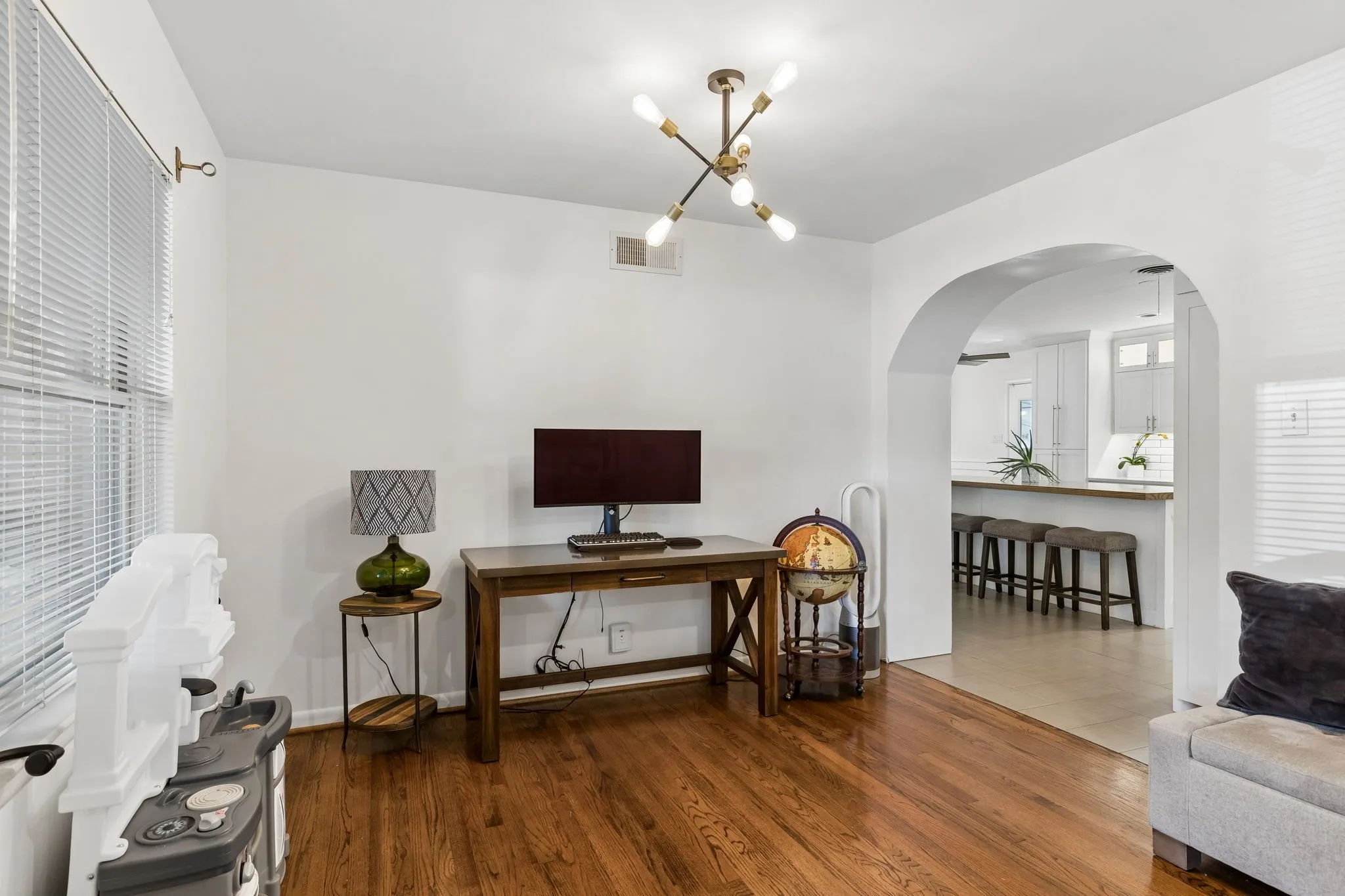 Hardwood flooring, arched doorway, and multi-light industrial-style chandelier