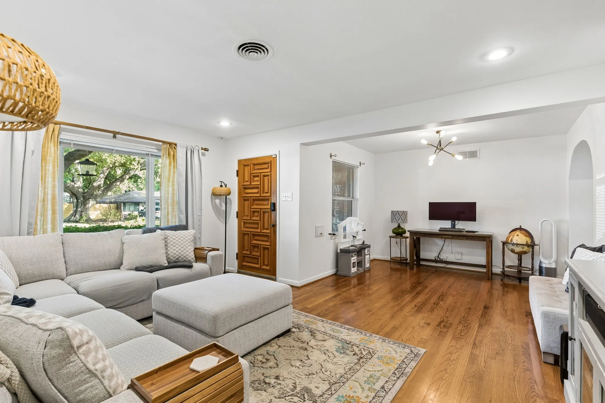 Living space featuring hardwood flooring, natural wood geometric patterned front door, recessed lighting, and arched doorway