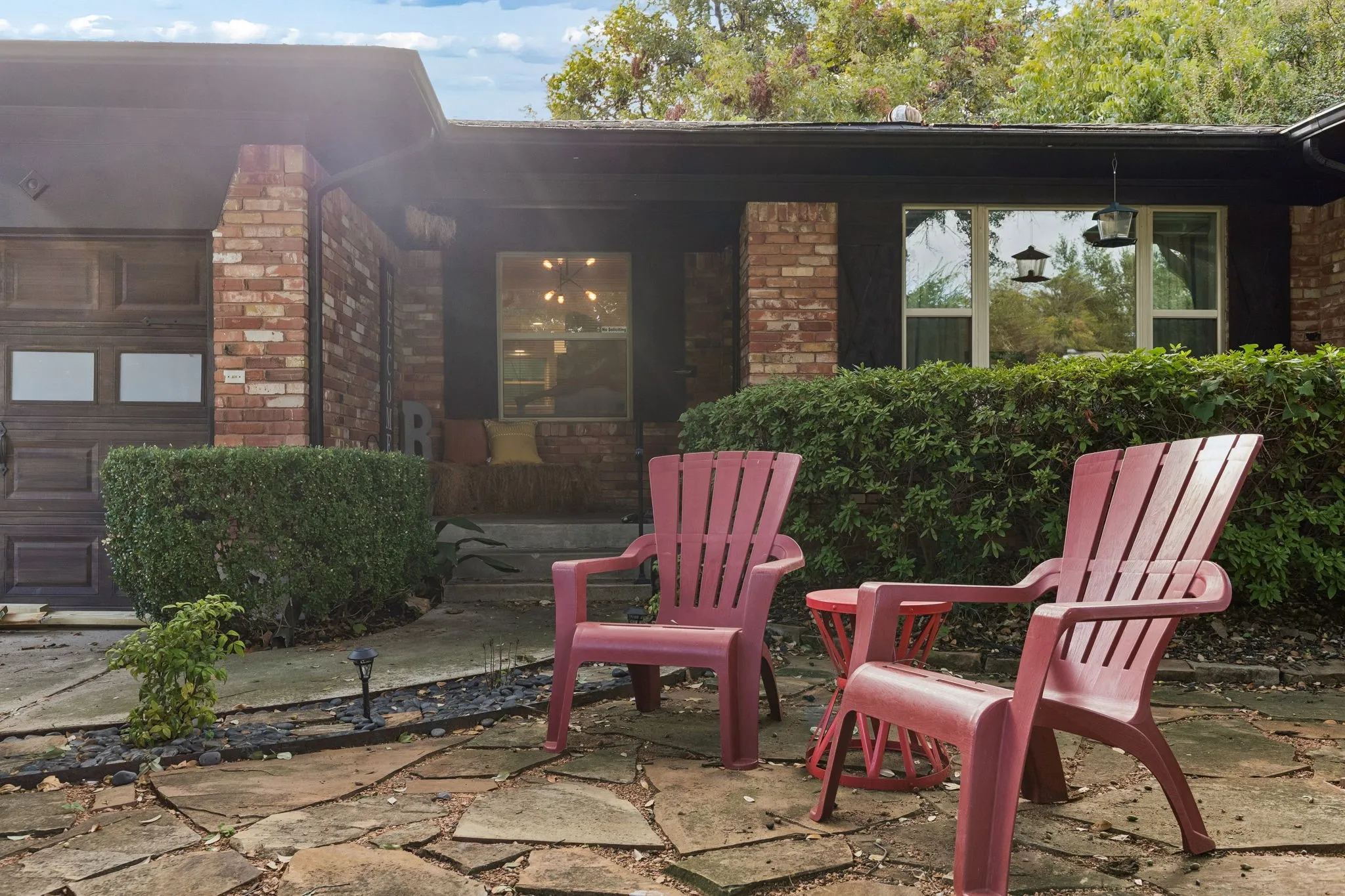 Exterior facade featuring a combination of red brick masonry and dark trim, flagstone patio, and integrated garage with frosted glass panels