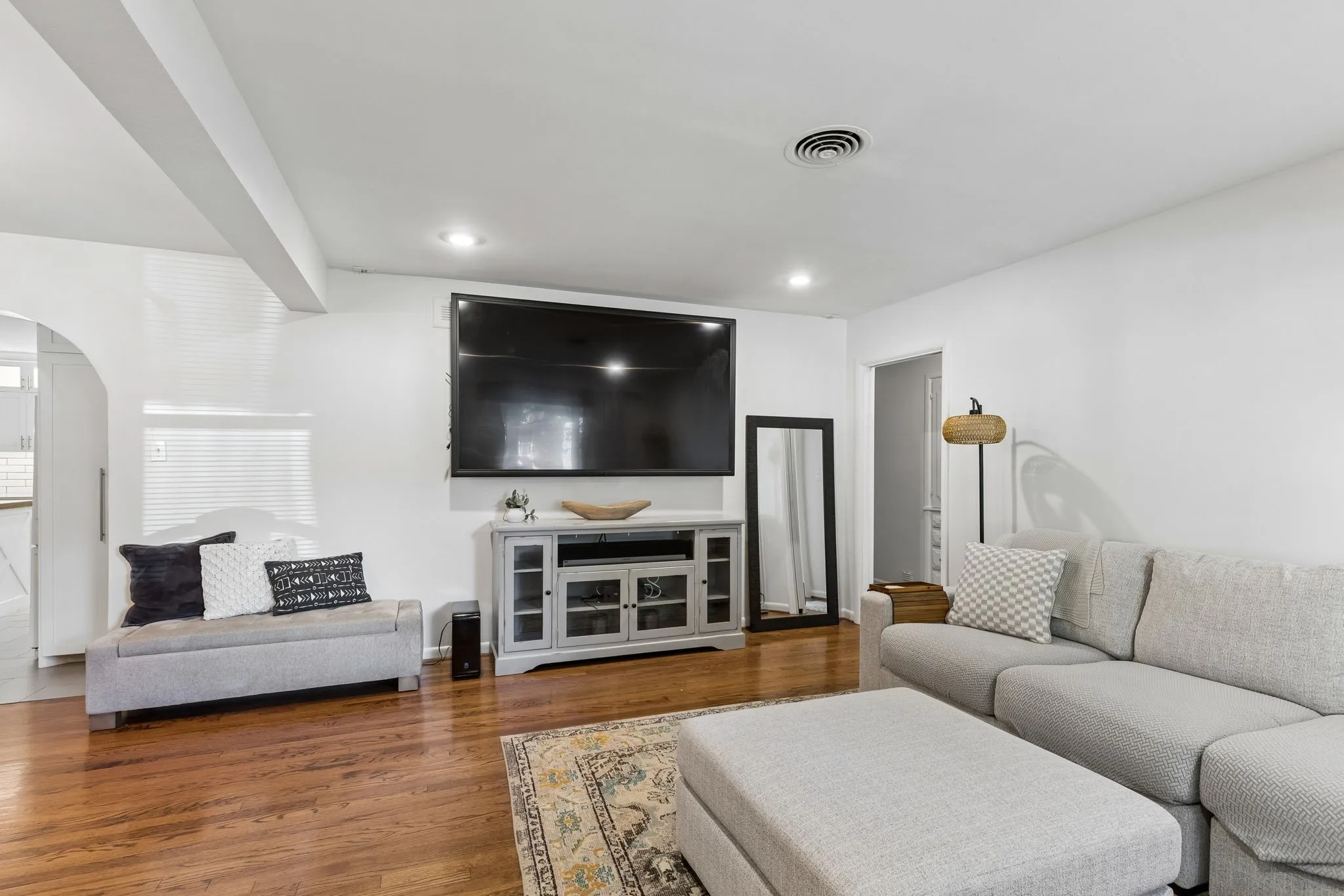 Living area featuring wood-finish flooring, recessed lighting, and a distinctive arched doorway