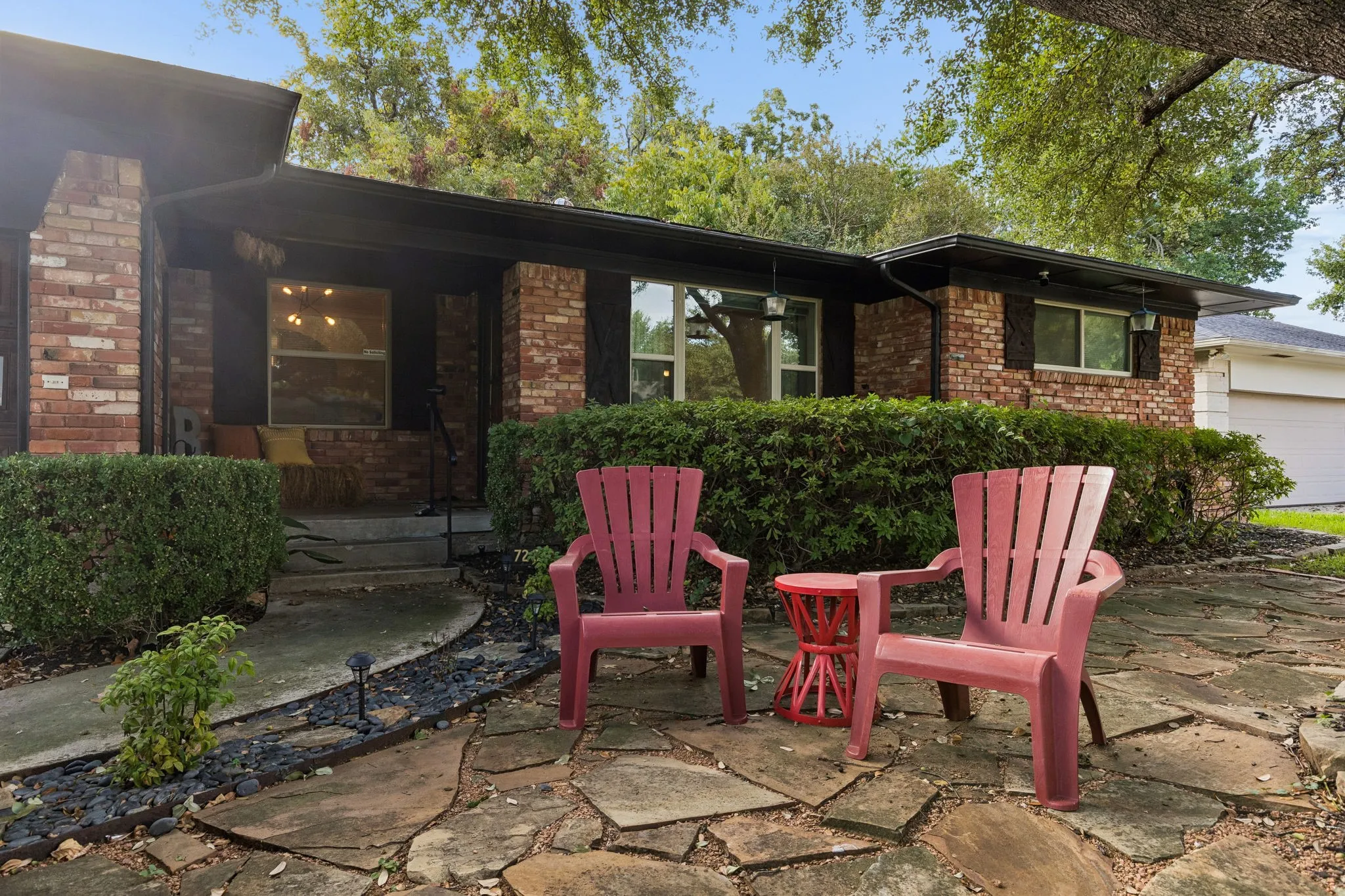 Single-story brick exterior featuring a flagstone patio, mature landscaping, and multi-pane windows
