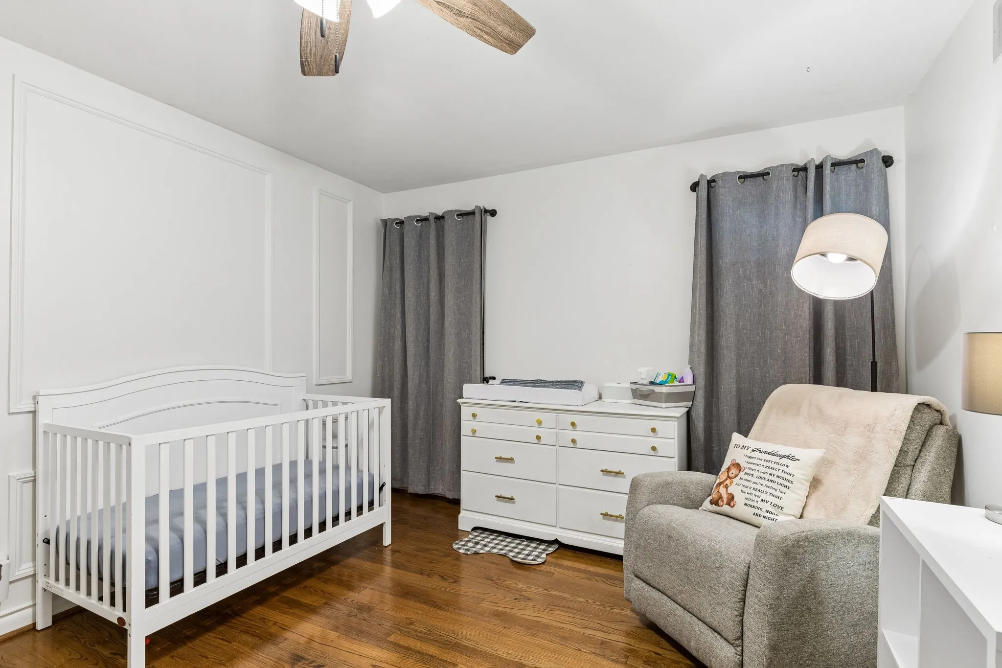 Interior space featuring wood-finish flooring, wall molding accents, and a ceiling fan with light fixture