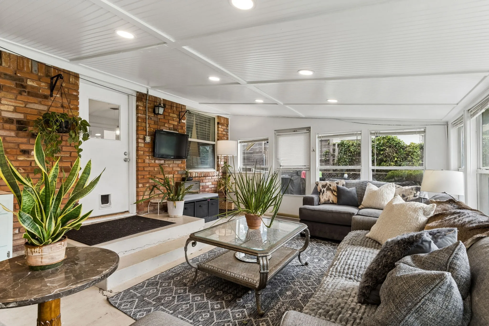 Sunroom featuring exposed brick walls, a paneled ceiling with recessed lighting, and expansive windows
