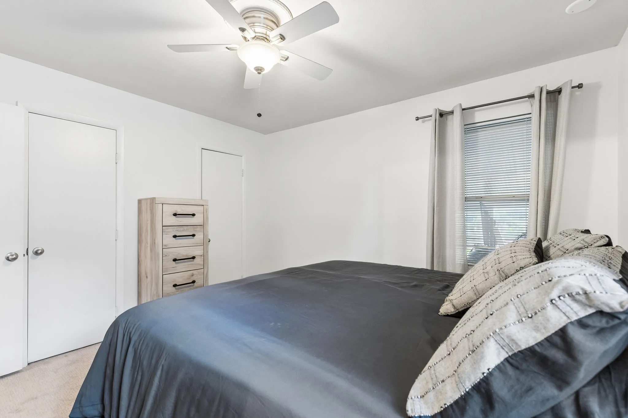 Neutral-toned carpet, white walls, ceiling fan with integrated lighting, and dual-door closet