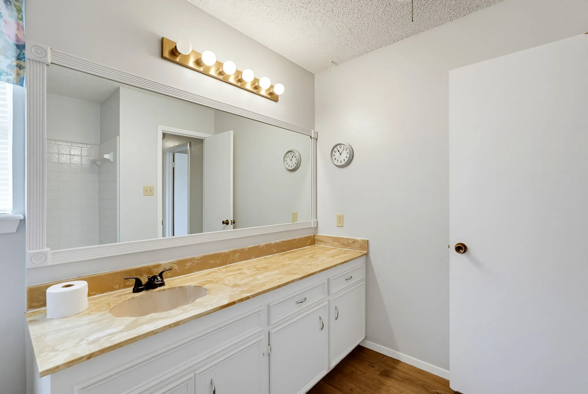 A framed mirror doubles the brightness, and the wall clock keeps mornings on schedule.