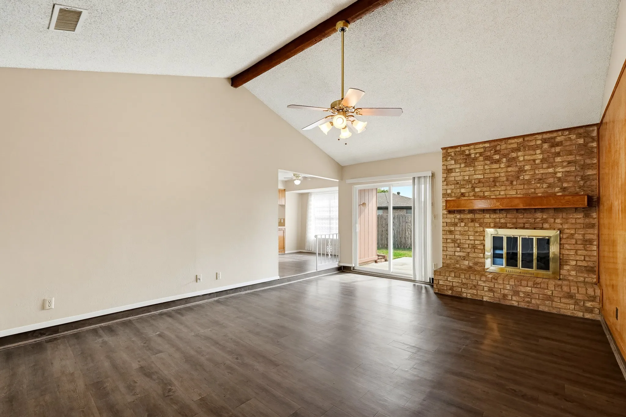 A brick hearth and a wall of warm timber, with the patio just steps away.