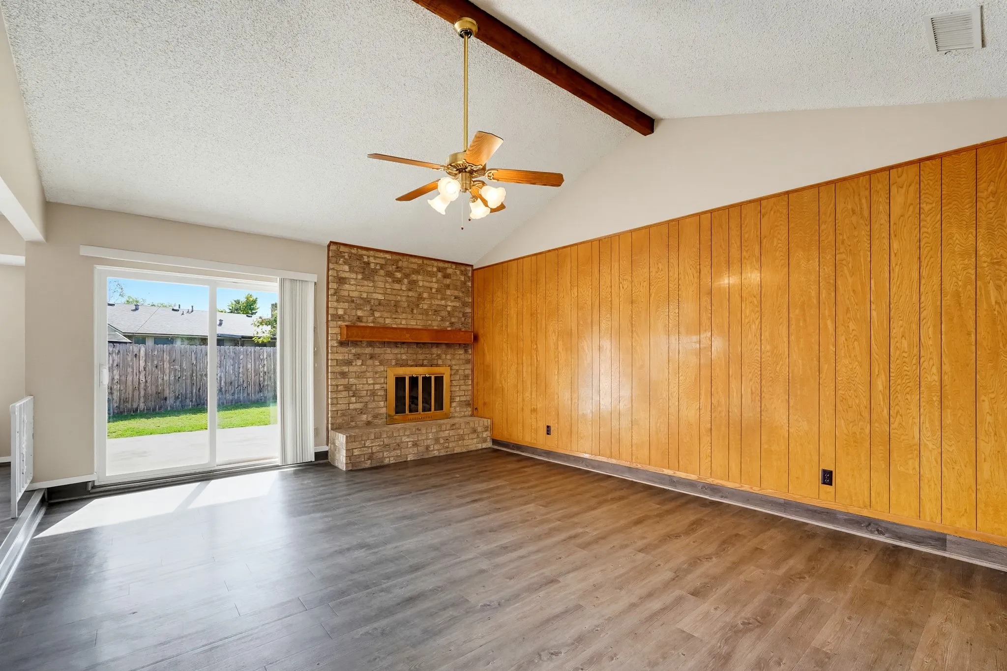 Vaulted ceilings and a rustic beam, with a sliding door that sends sunshine pouring in.