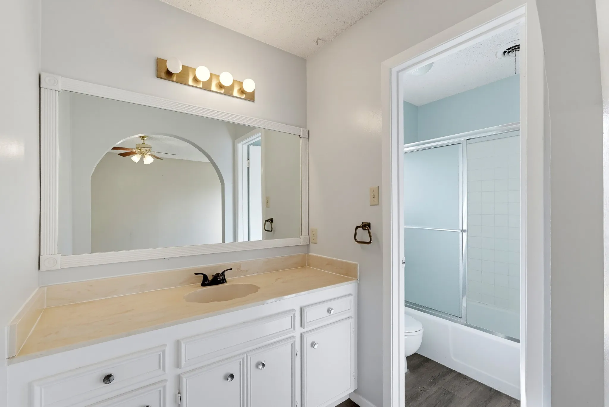 A bright mirror and roomy vanity sit just outside the bath-and-shower combo.