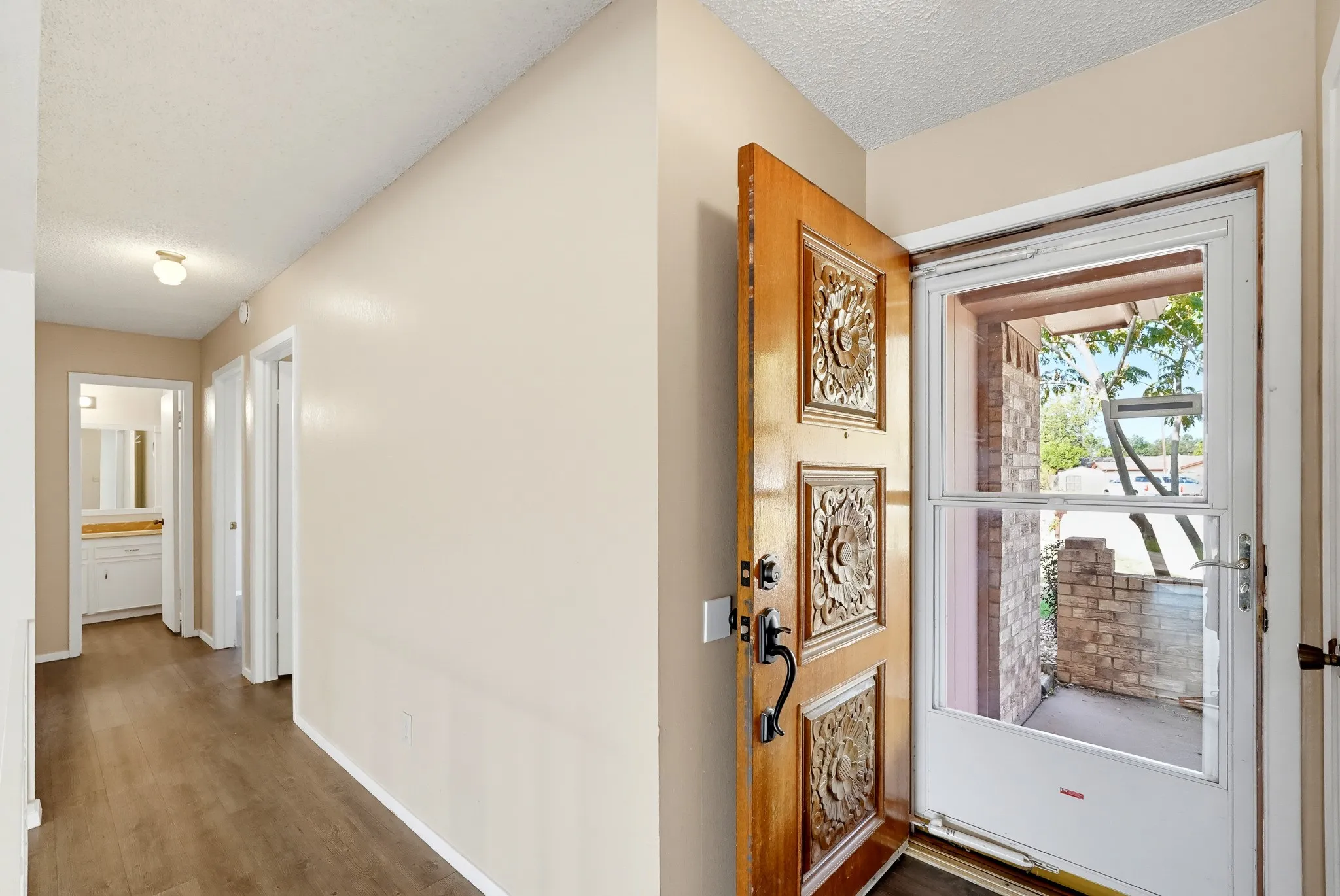 A carved wooden door makes the welcome, and the hall leads to the bedrooms and bath.