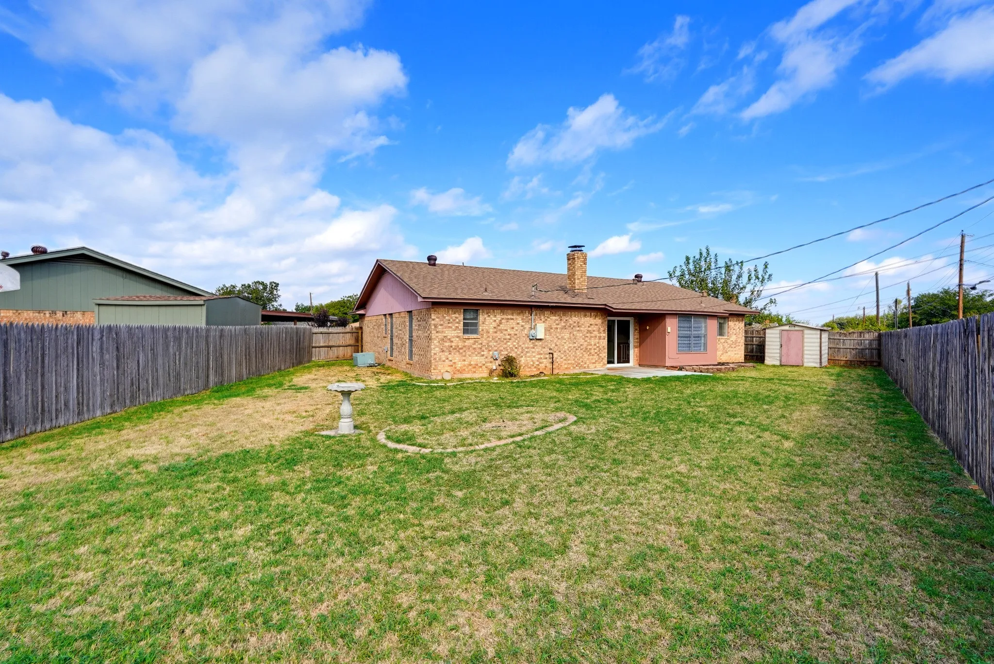 Sliding doors open to a concrete patio, and stepping stones wander across the lawn.