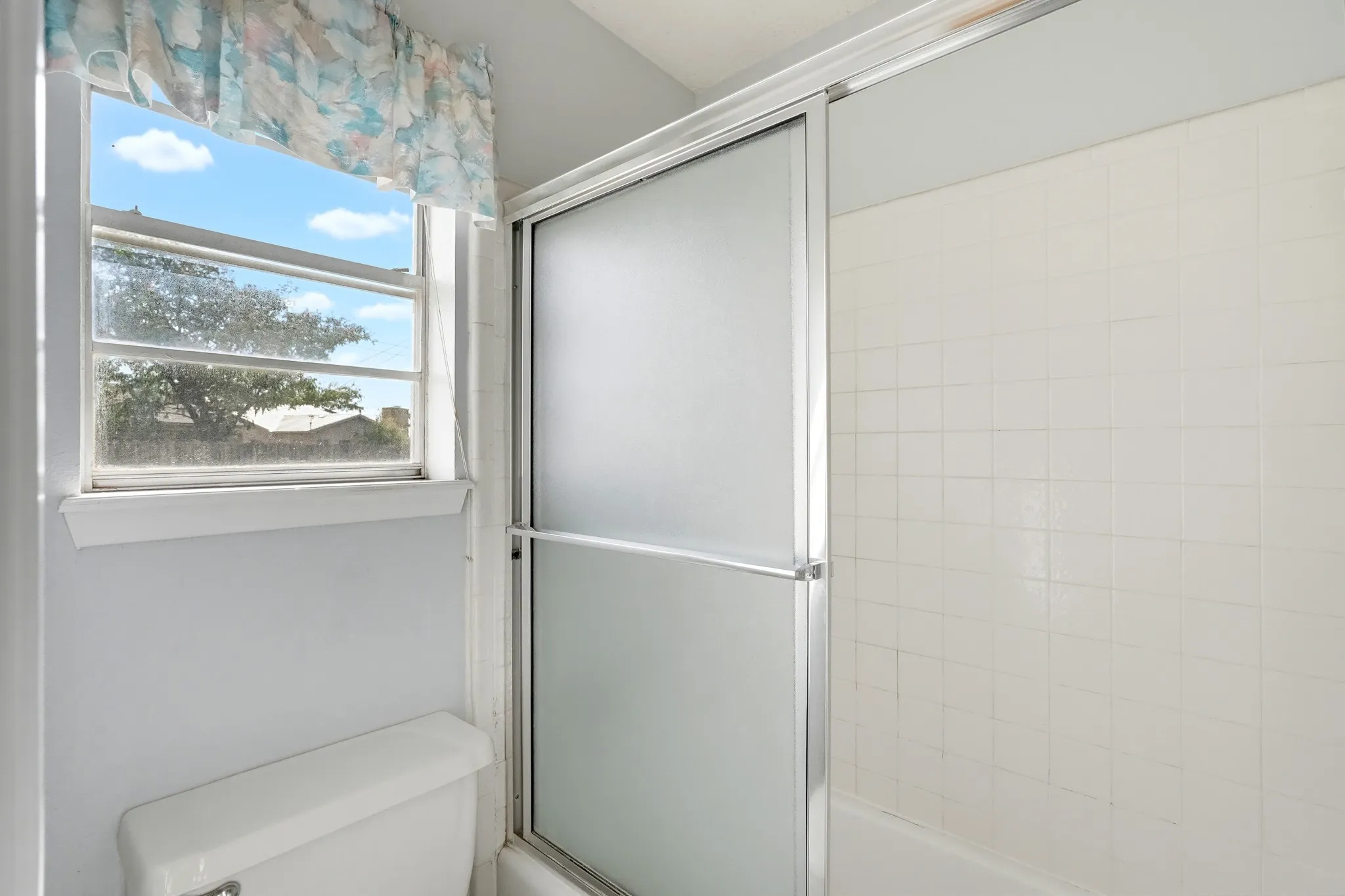 Frosted sliding doors keep things private while a window lets natural light drift in.