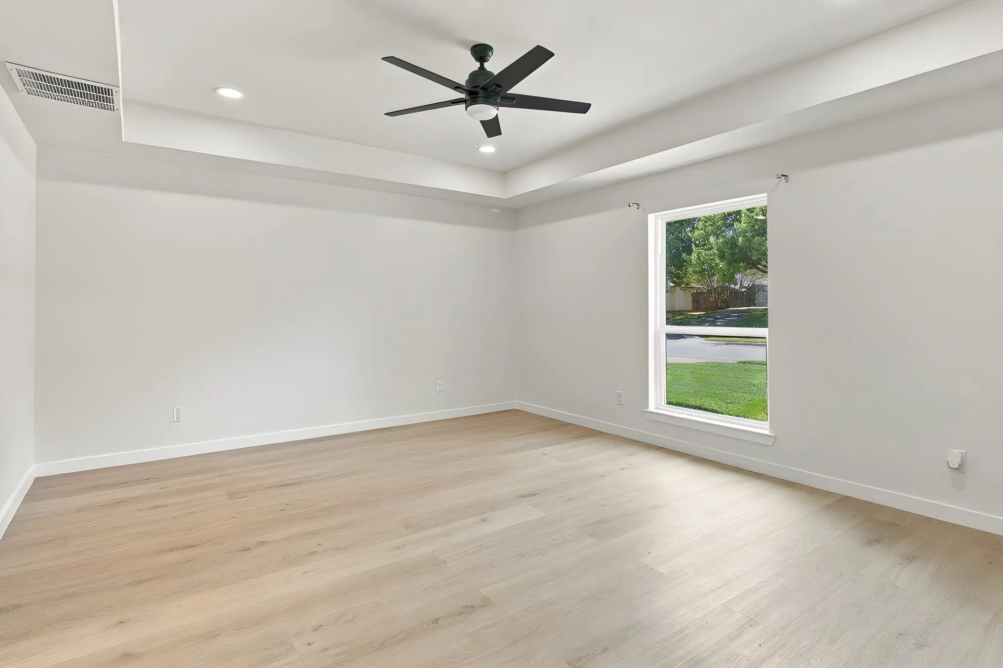 Interior space featuring a tray ceiling, wood-finish flooring, a matte black ceiling fan, and recessed lighting