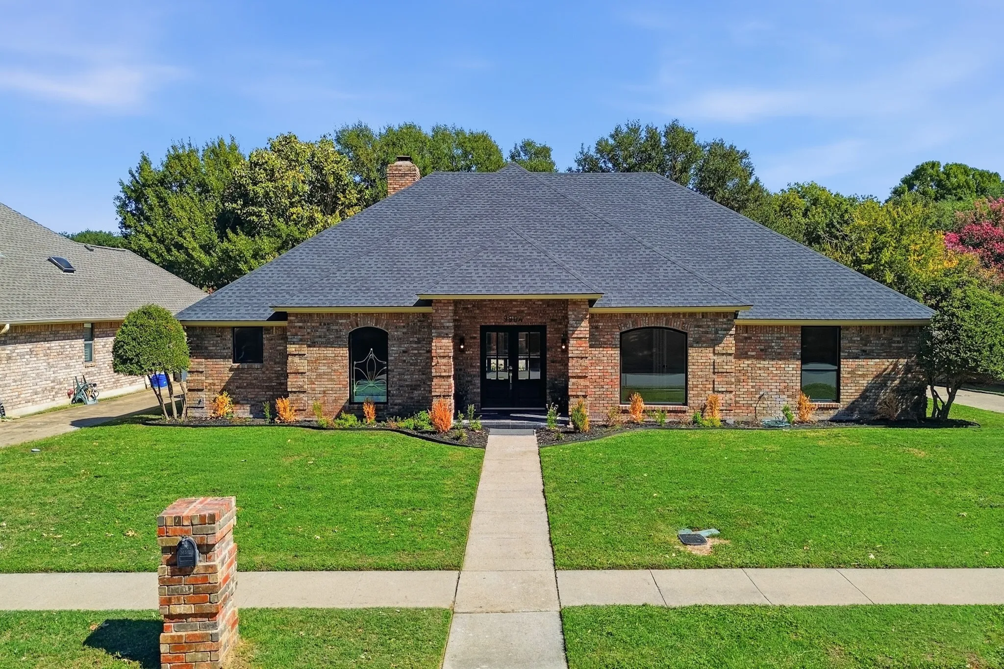 Brick exterior facade featuring a multi-gabled roof, arched window detailing, and an arched double-door entry