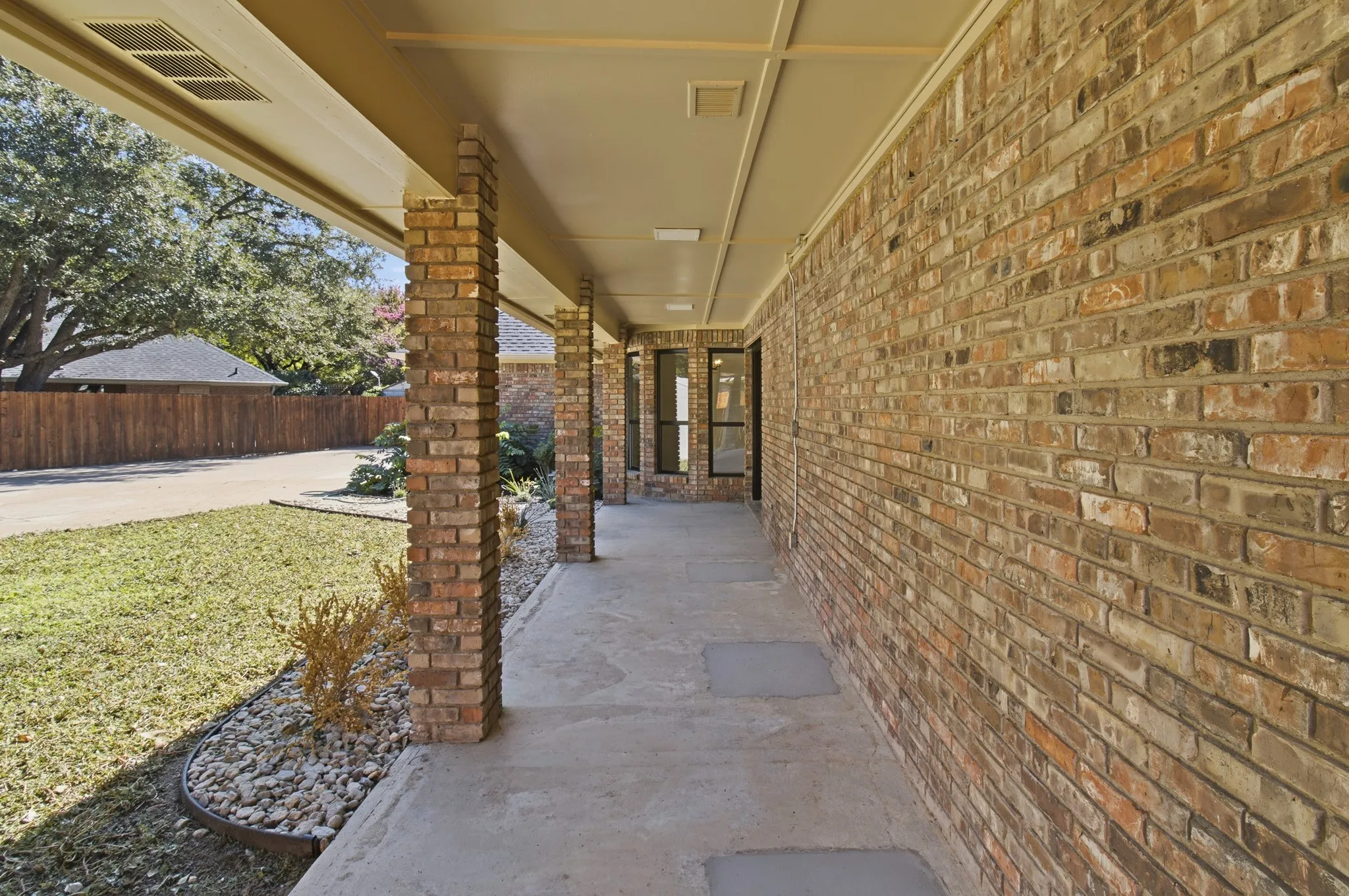 Covered exterior porch featuring brick structural columns, masonry wall siding, and concrete flooring