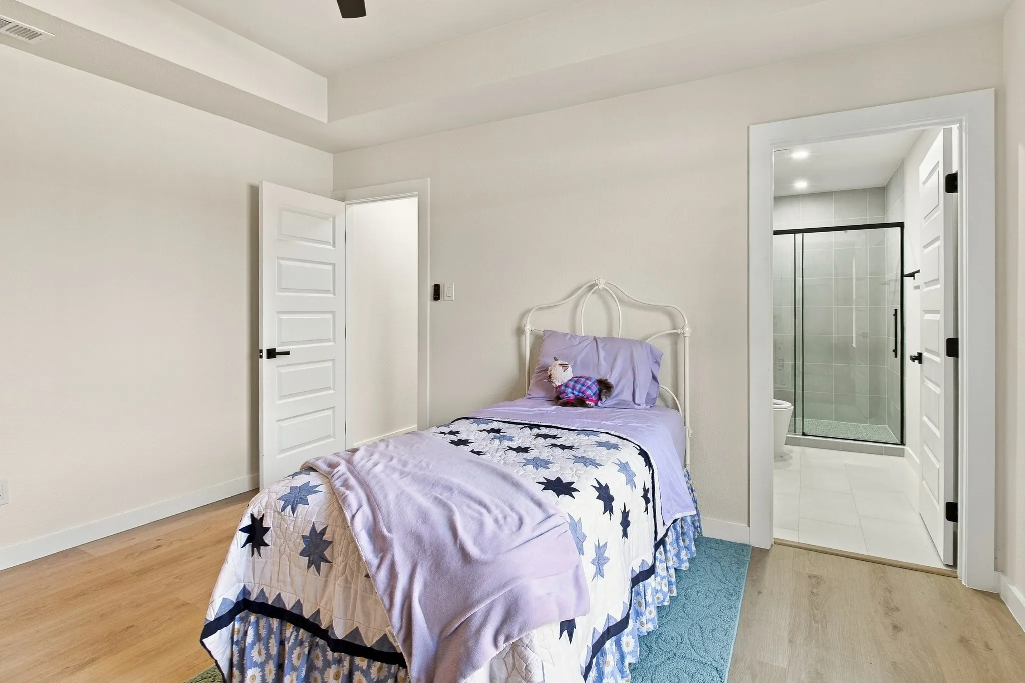 Room featuring tray ceilings, wood-finish flooring, and shaker-style interior doors