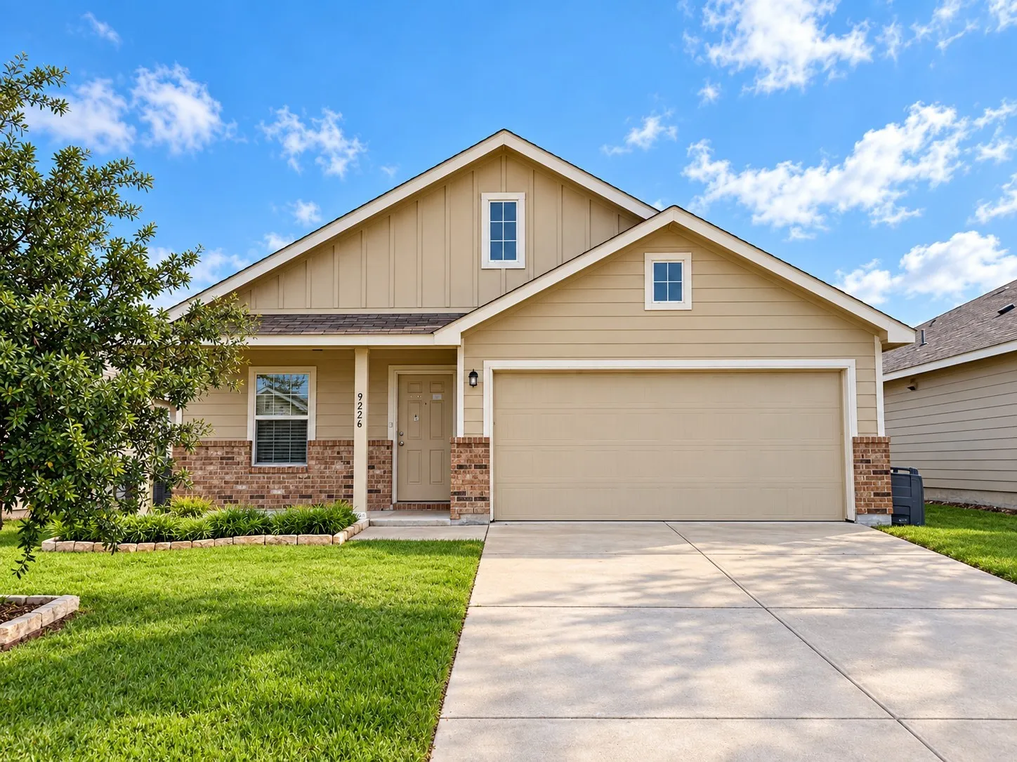 Front exterior featuring a two-car garage, brick accents, covered entry, and a manicured lawn