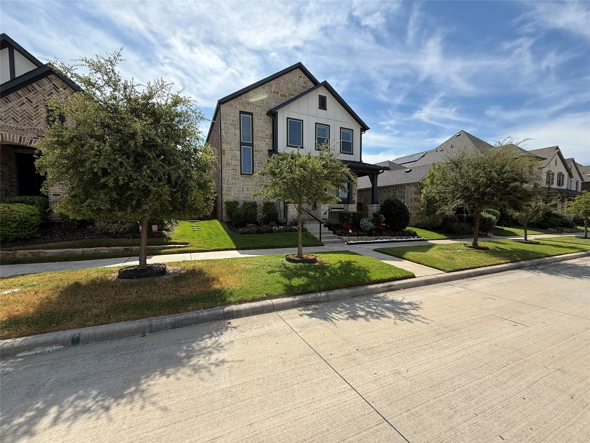 Multi-story residence with a stone and board-and-batten facade, peaked rooflines, and manicured landscaping