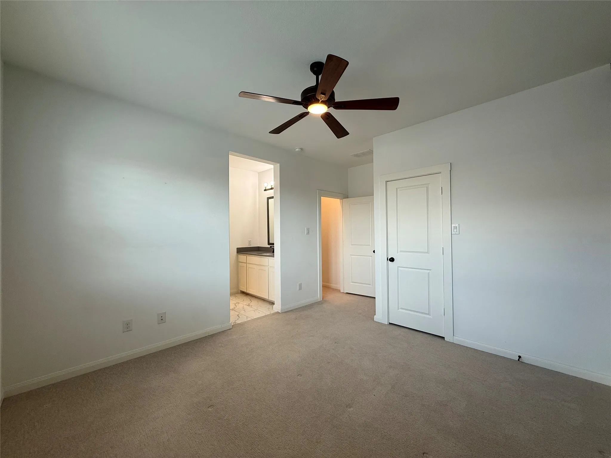 Neutral-toned carpeting, ceiling fan with integrated lighting, and white paneled doors