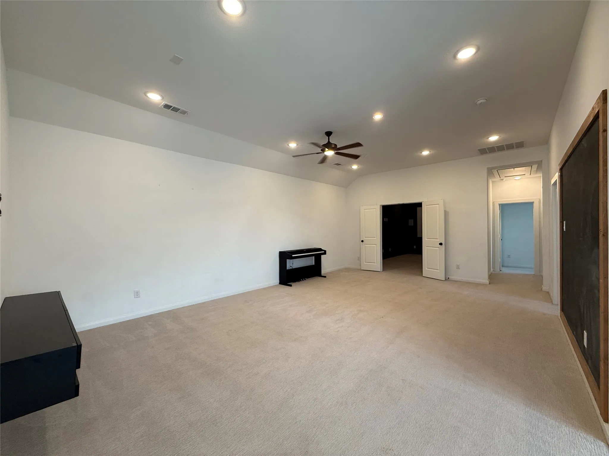 Spacious interior featuring high ceilings, recessed lighting, a ceiling fan, neutral carpeting, and white double doors