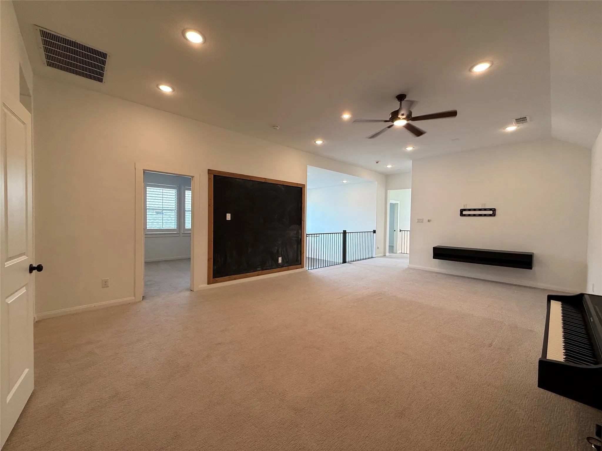 Vaulted ceilings featuring recessed lighting and a ceiling fan, a large framed wall-mounted chalkboard, and a dark-finished floating media console