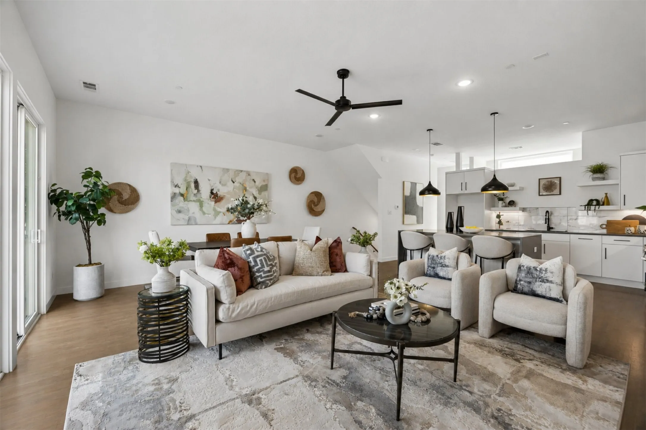 Open-concept interior featuring wood-finish flooring, recessed lighting, a modern ceiling fan, and a kitchen equipped with cabinetry and stone-finish countertops