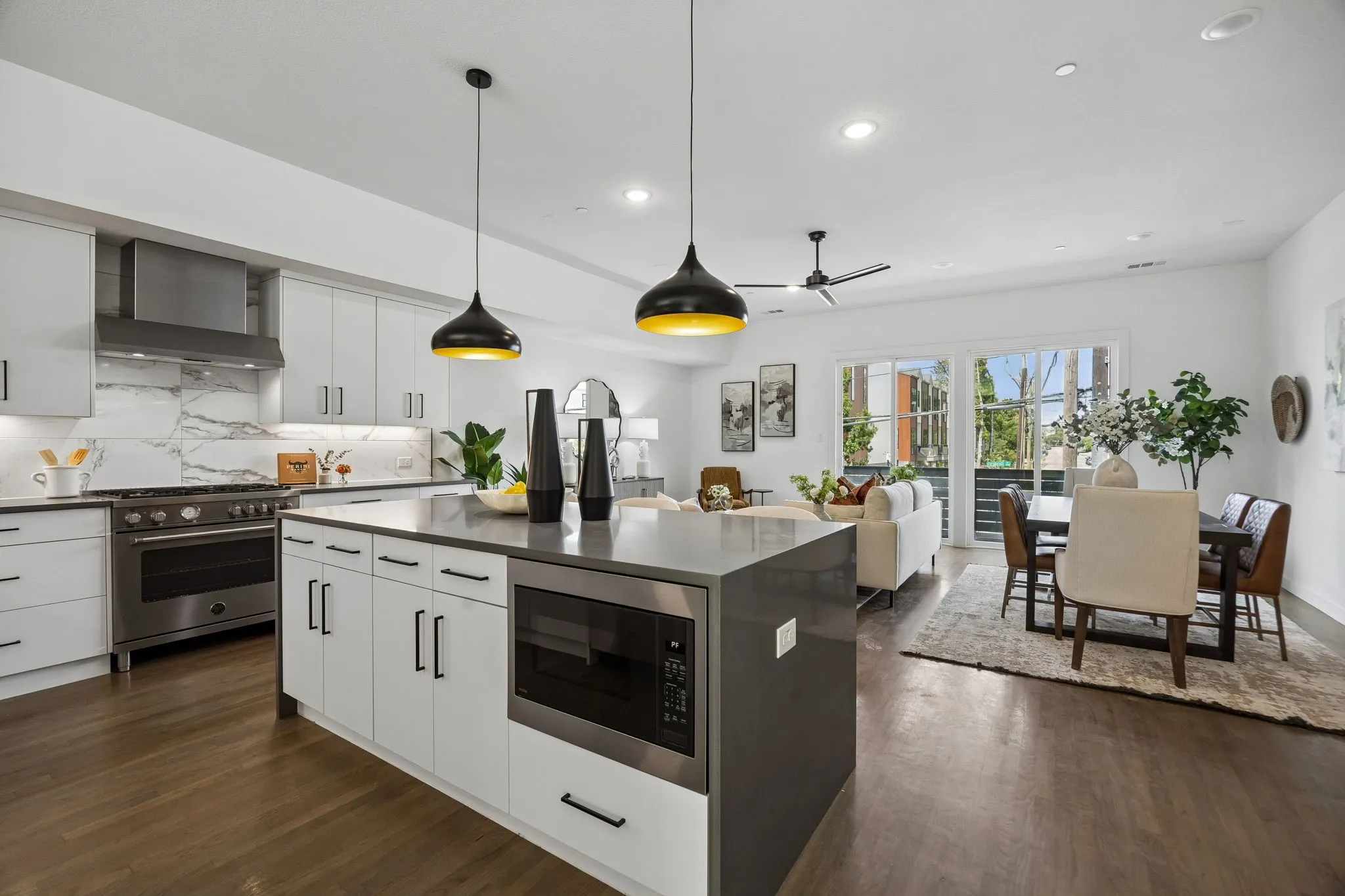 Kitchen featuring a center island with solid-surface countertop, flat-panel cabinetry, professional-style stainless steel range, full-height stone-look backsplash, and dual pendant lighting