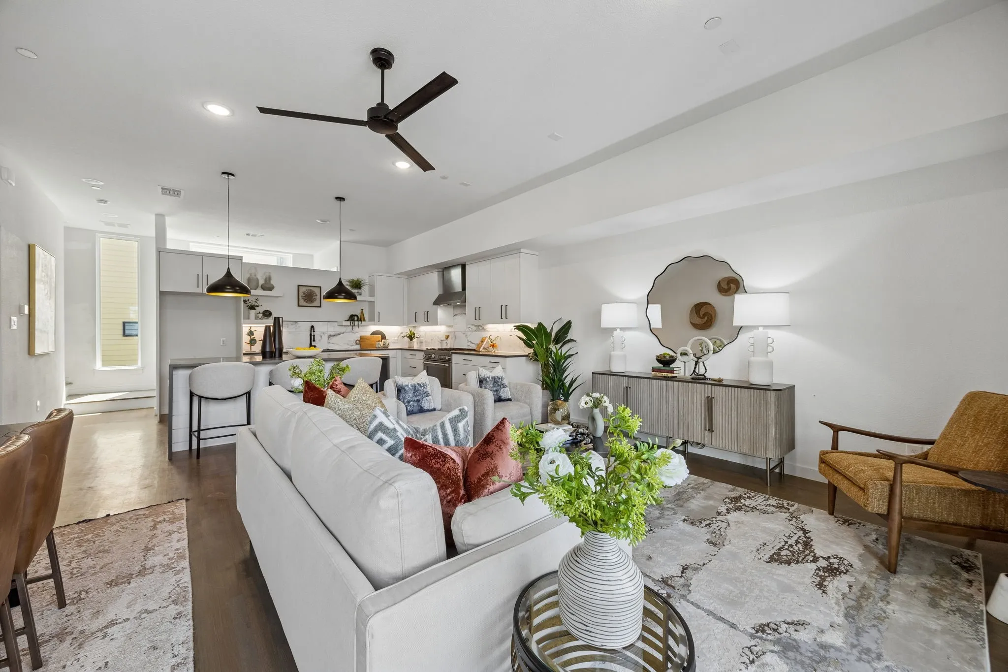 Open-concept living space featuring high ceilings, wood-finish flooring, a kitchen island with pendant lighting, and modern cabinetry