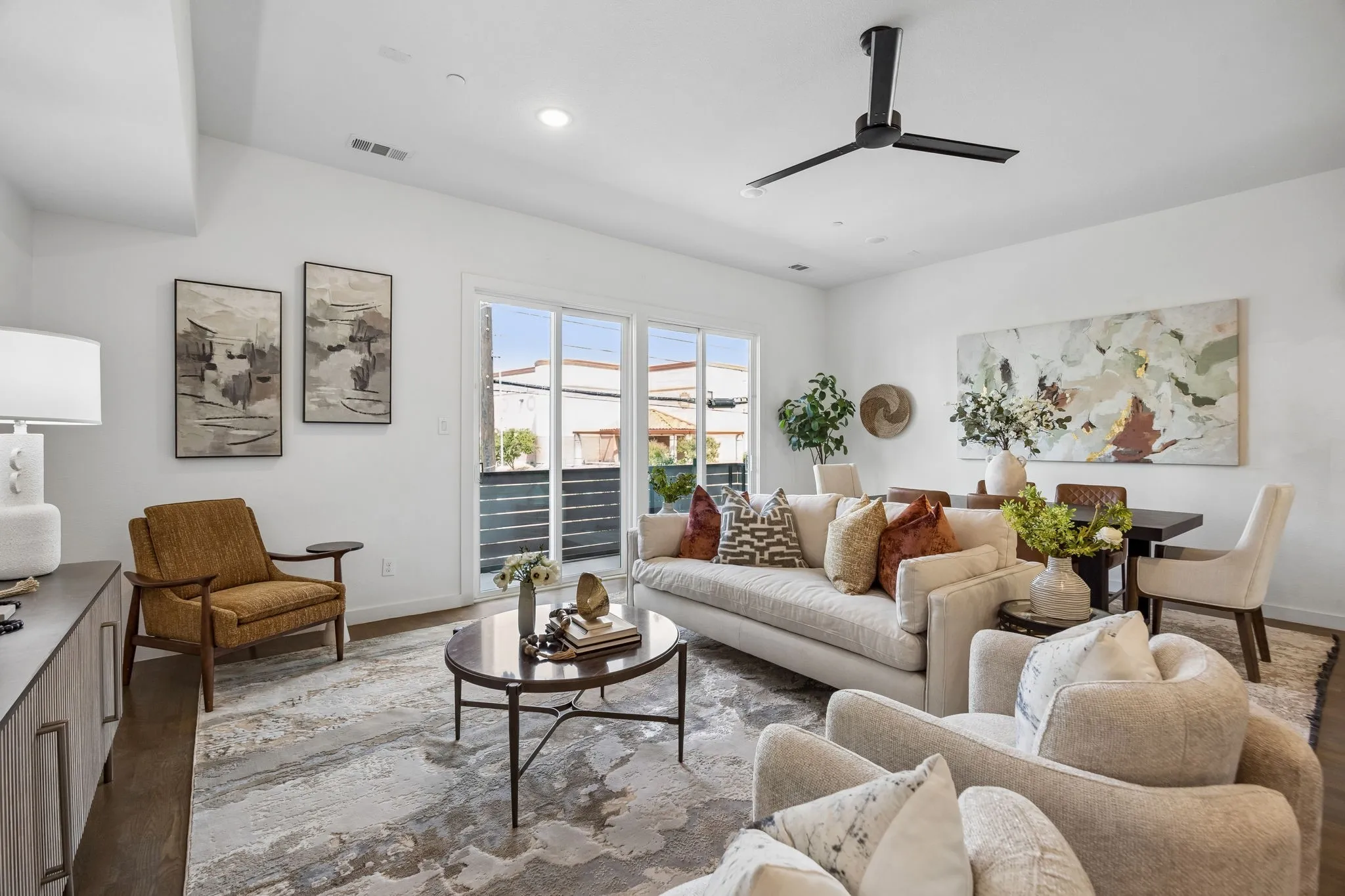 Open floor plan featuring wood-finish flooring, recessed lighting, matte black ceiling fan, and sliding glass doors with exterior balcony access