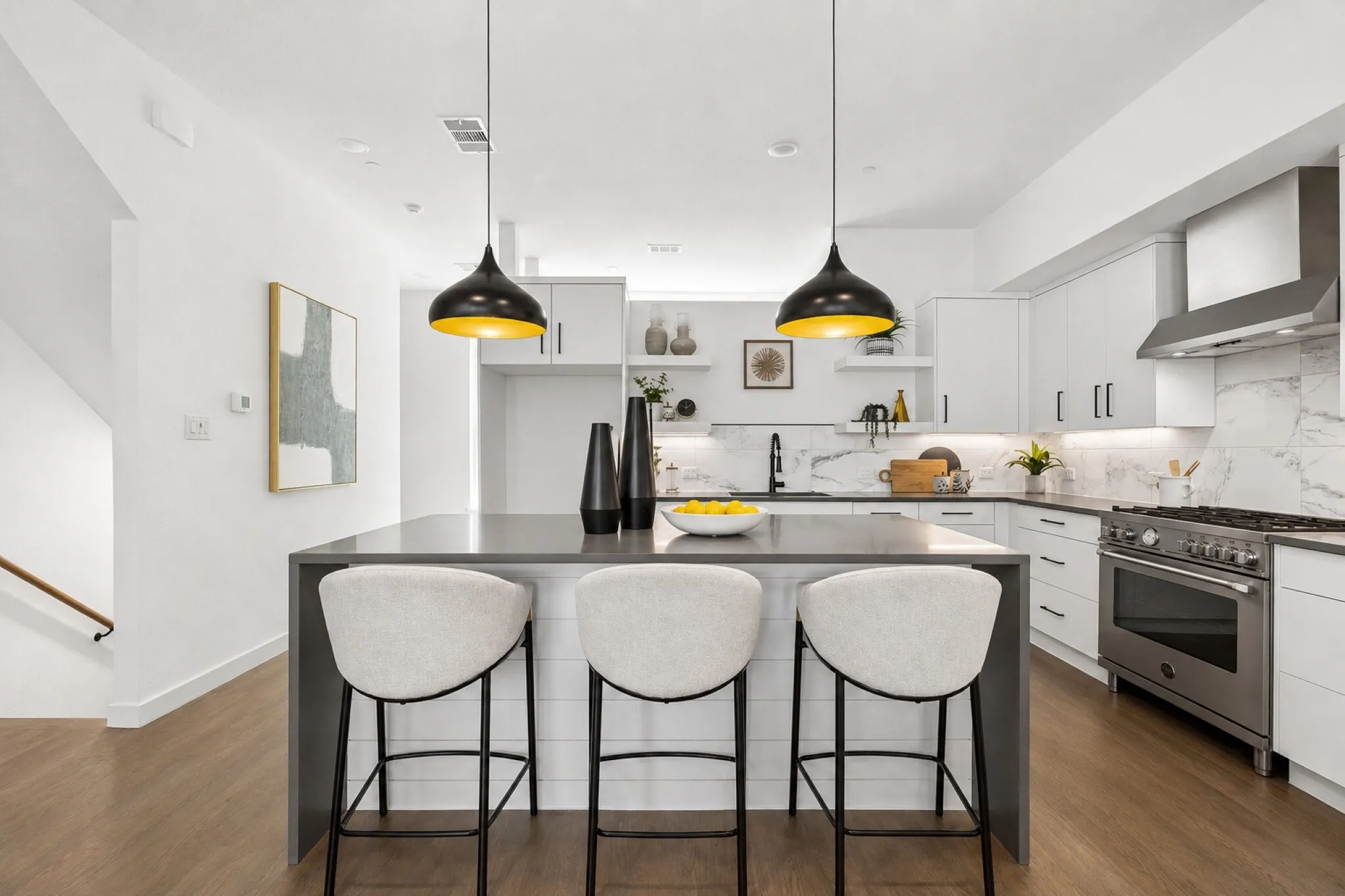 Kitchen featuring a waterfall-edge center island, white cabinetry, professional-grade stainless steel range, patterned stone-finish backsplash, and wood-finish flooring