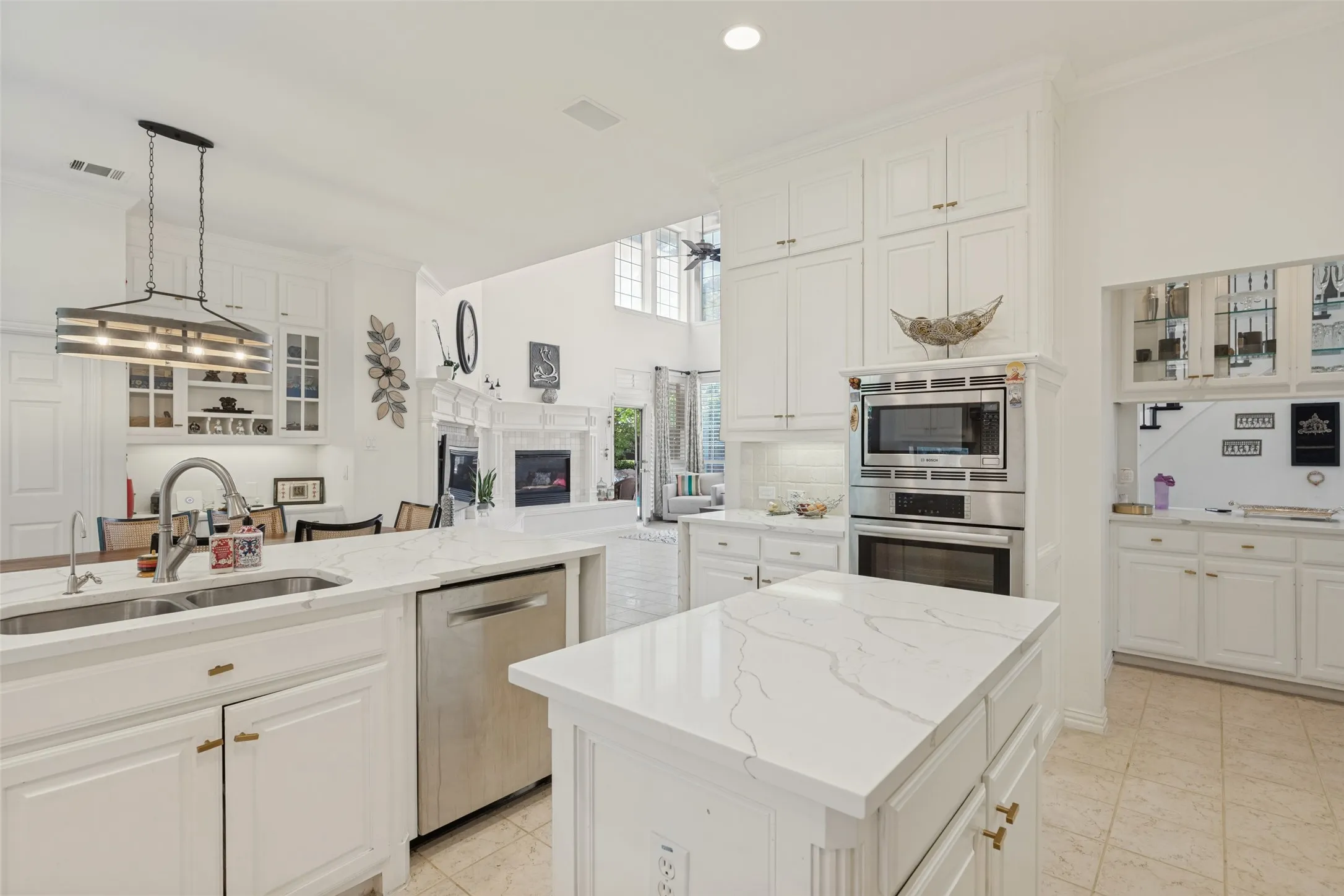 Kitchen featuring white cabinetry, stone-finish countertops, stainless steel appliances, a central island, and an over-counter pendant light fixture