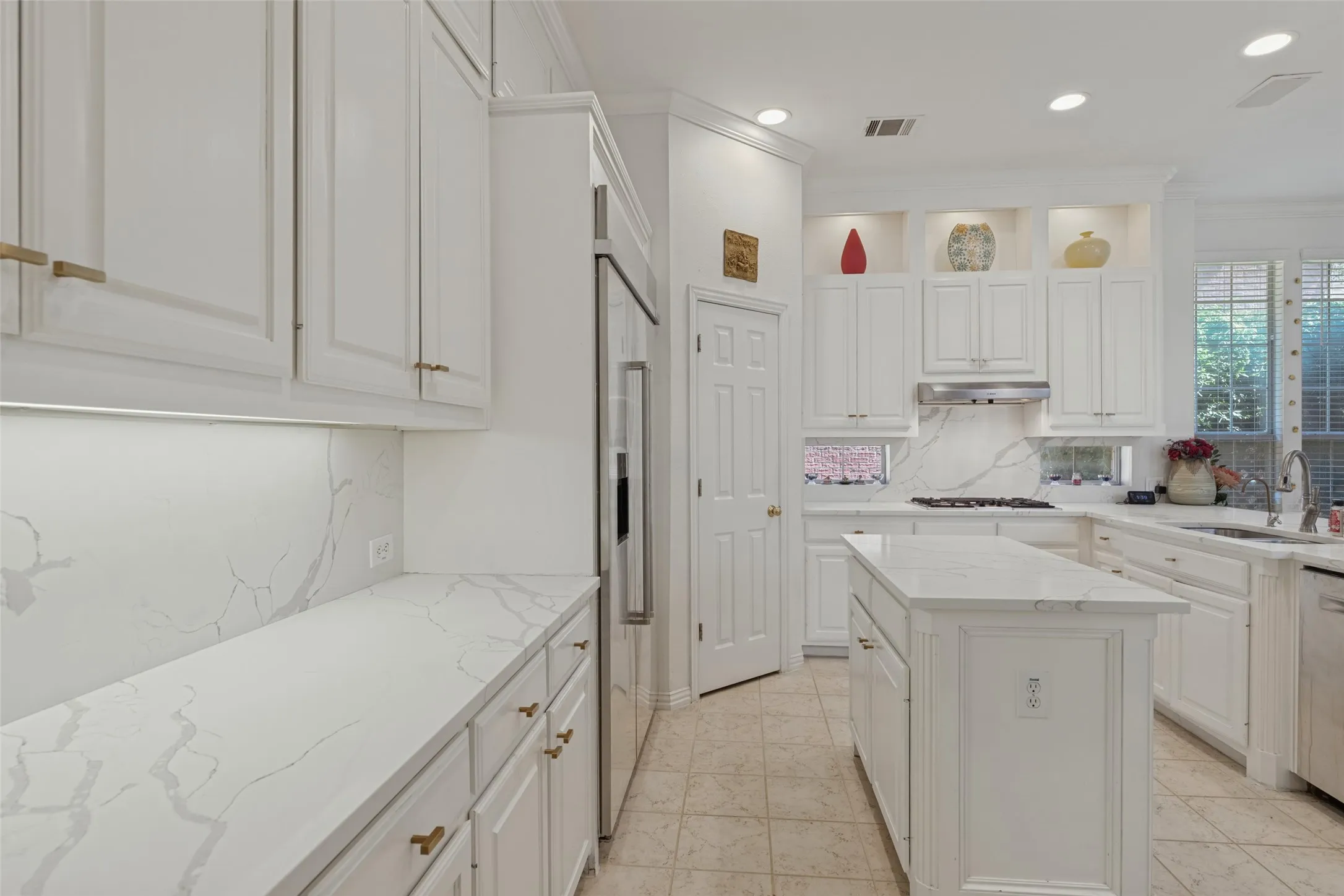 Kitchen featuring white cabinetry, stone-surface countertops with continuous backsplashes, a central island, recessed lighting, and stainless-steel appliances