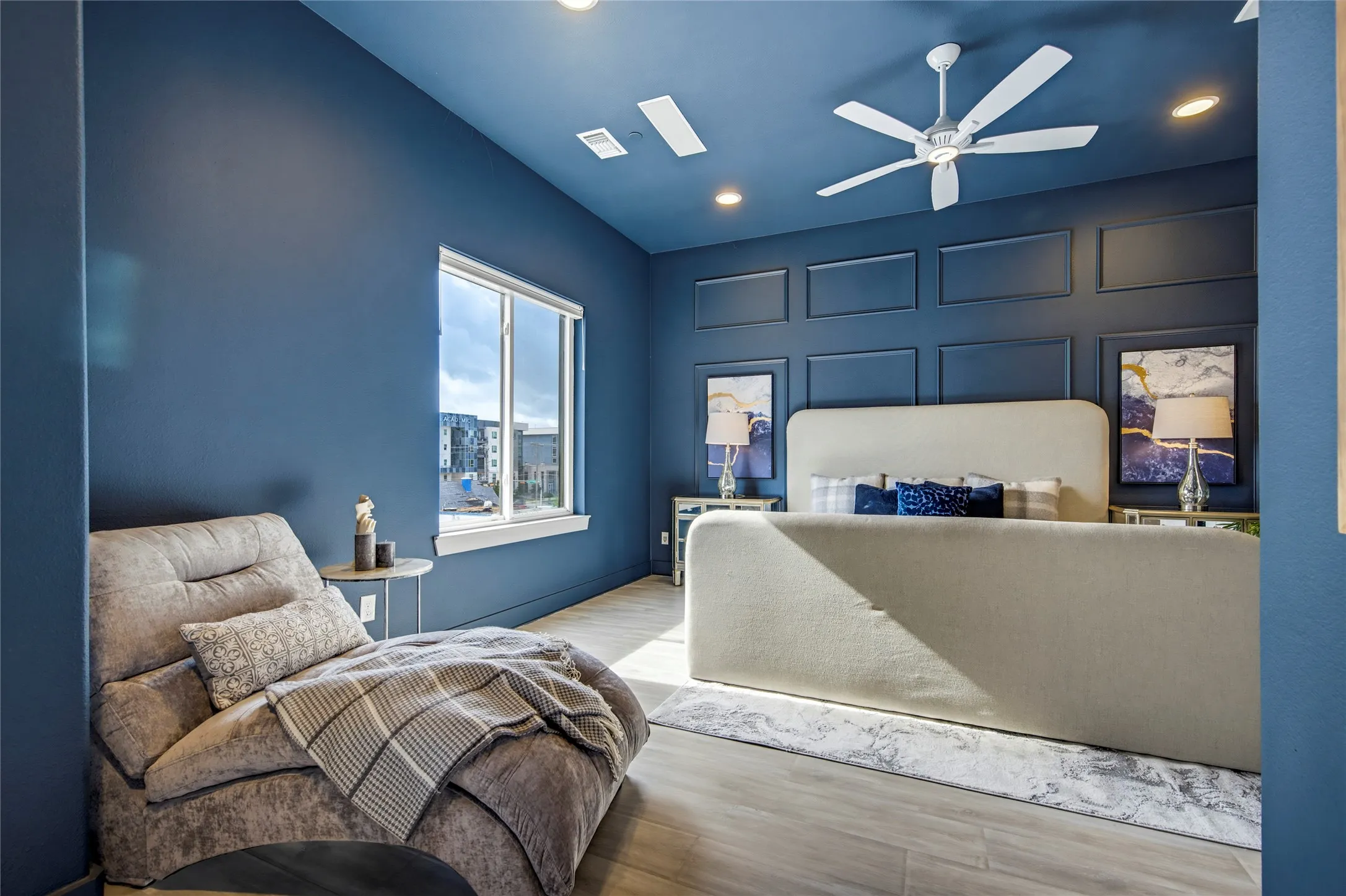 Bedroom featuring recessed ceiling lighting, a white ceiling fan, wood-finish flooring, and wall paneling