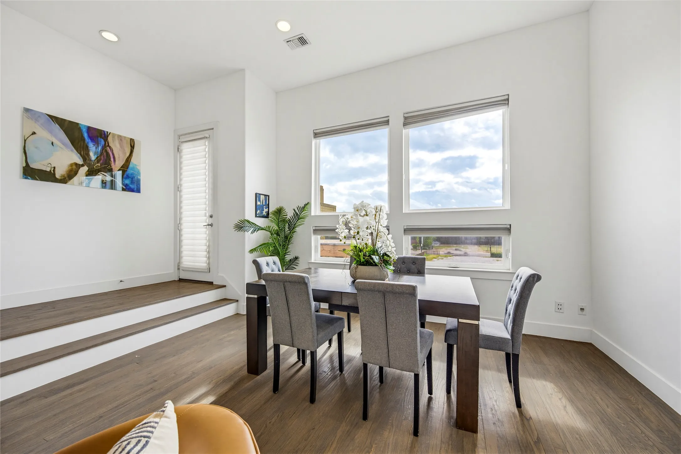 High ceilings with recessed lighting, large picture windows, elevated step-up landing, and wood-finish flooring