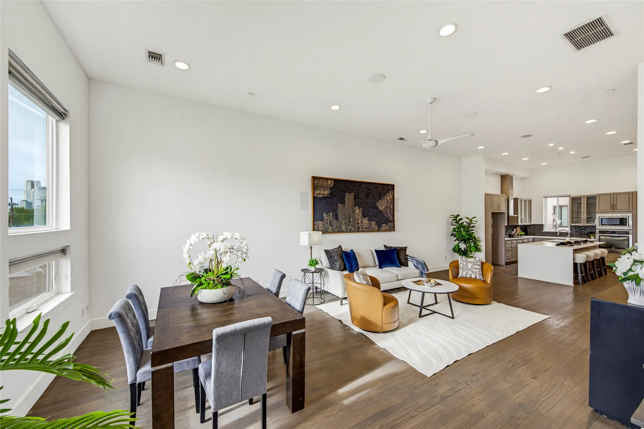 Open-concept living space featuring wood-finish flooring, recessed lighting, ceiling fan, and large windows with integrated blinds