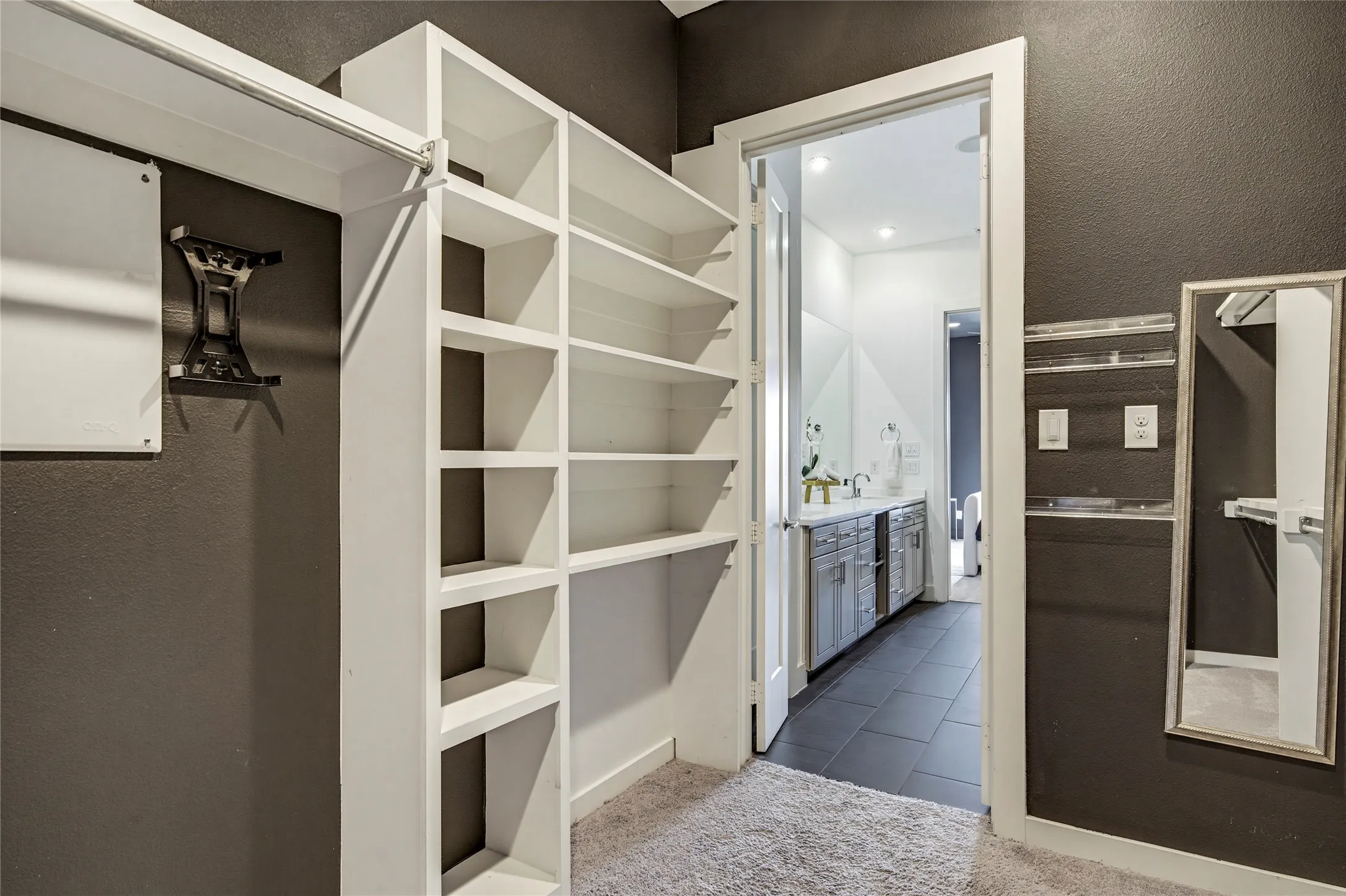Walk-in closet featuring custom white built-in shelving and hanging rods