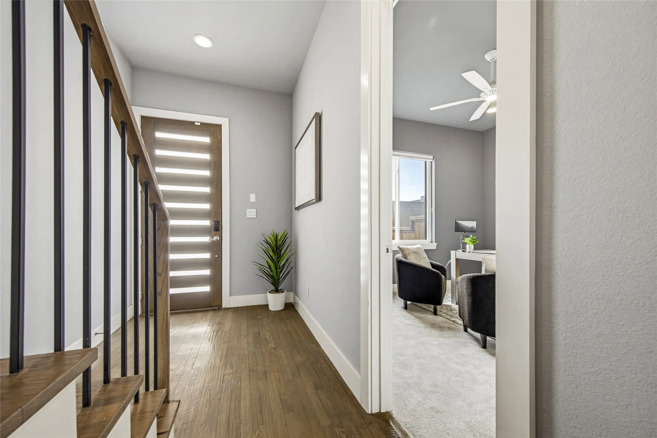 Entryway featuring wood-finish flooring, a horizontal paneled front door with glass inserts, and a staircase with metal balusters and wood handrails