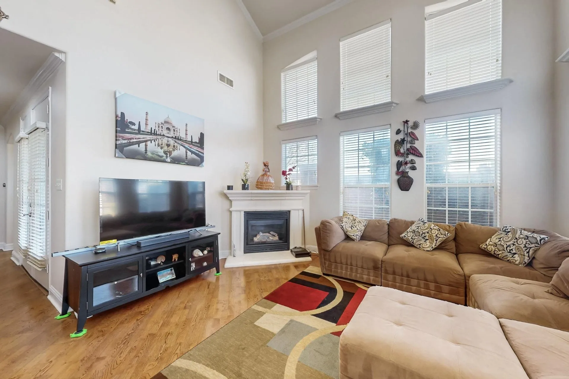 Vaulted ceilings, expansive windows, and a classic fireplace with a decorative mantel