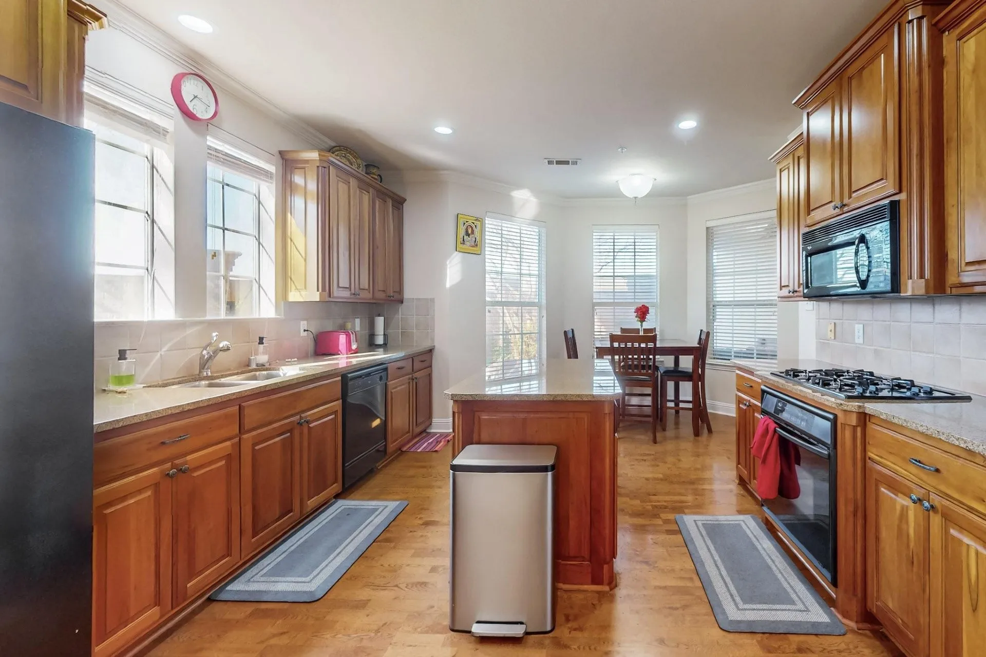 Kitchen featuring wood cabinetry, stone countertops, a center island, wood-finish flooring, and recessed lighting