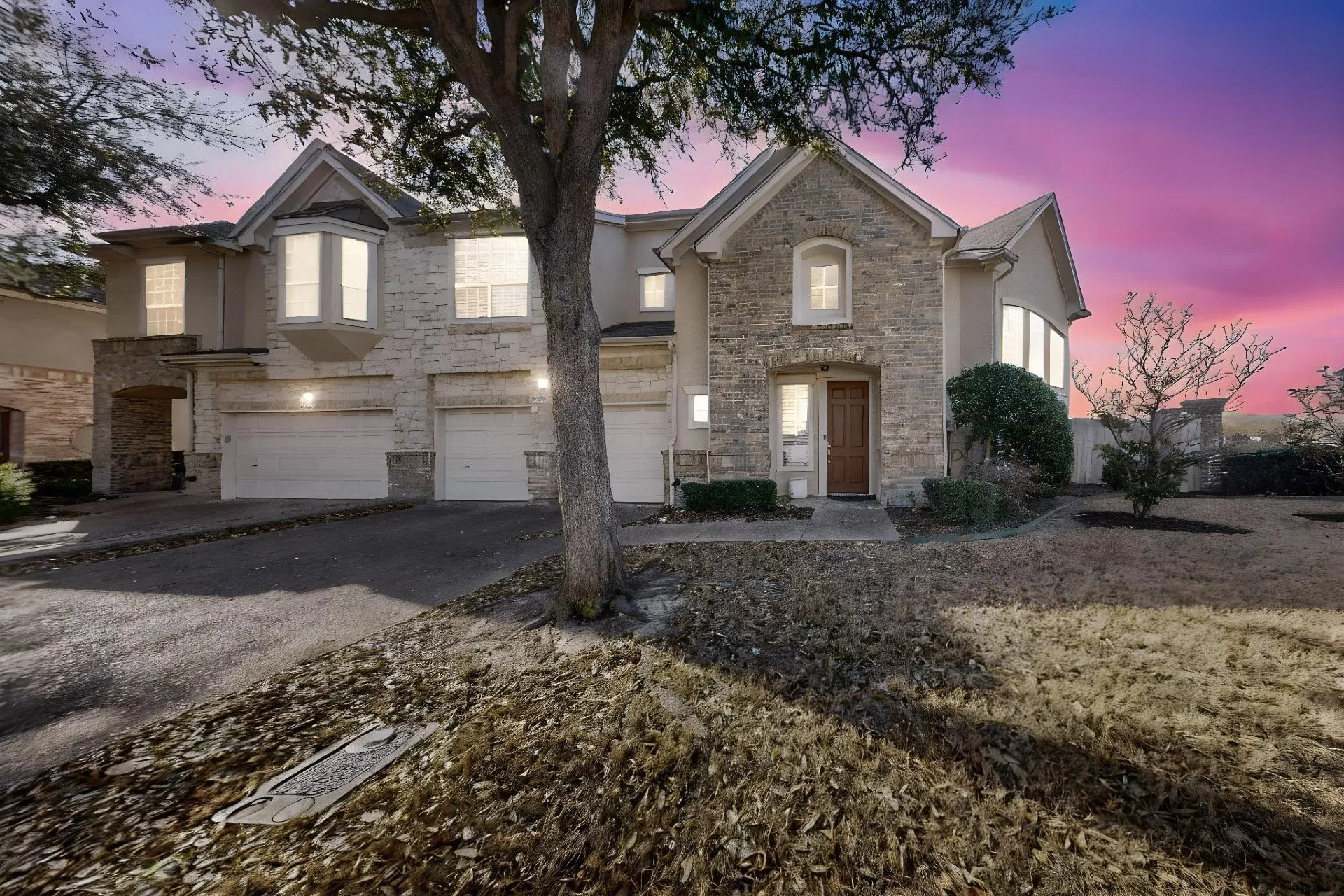 Multi-story exterior featuring a stone and stucco façade, triple-car garage, and arched entryway