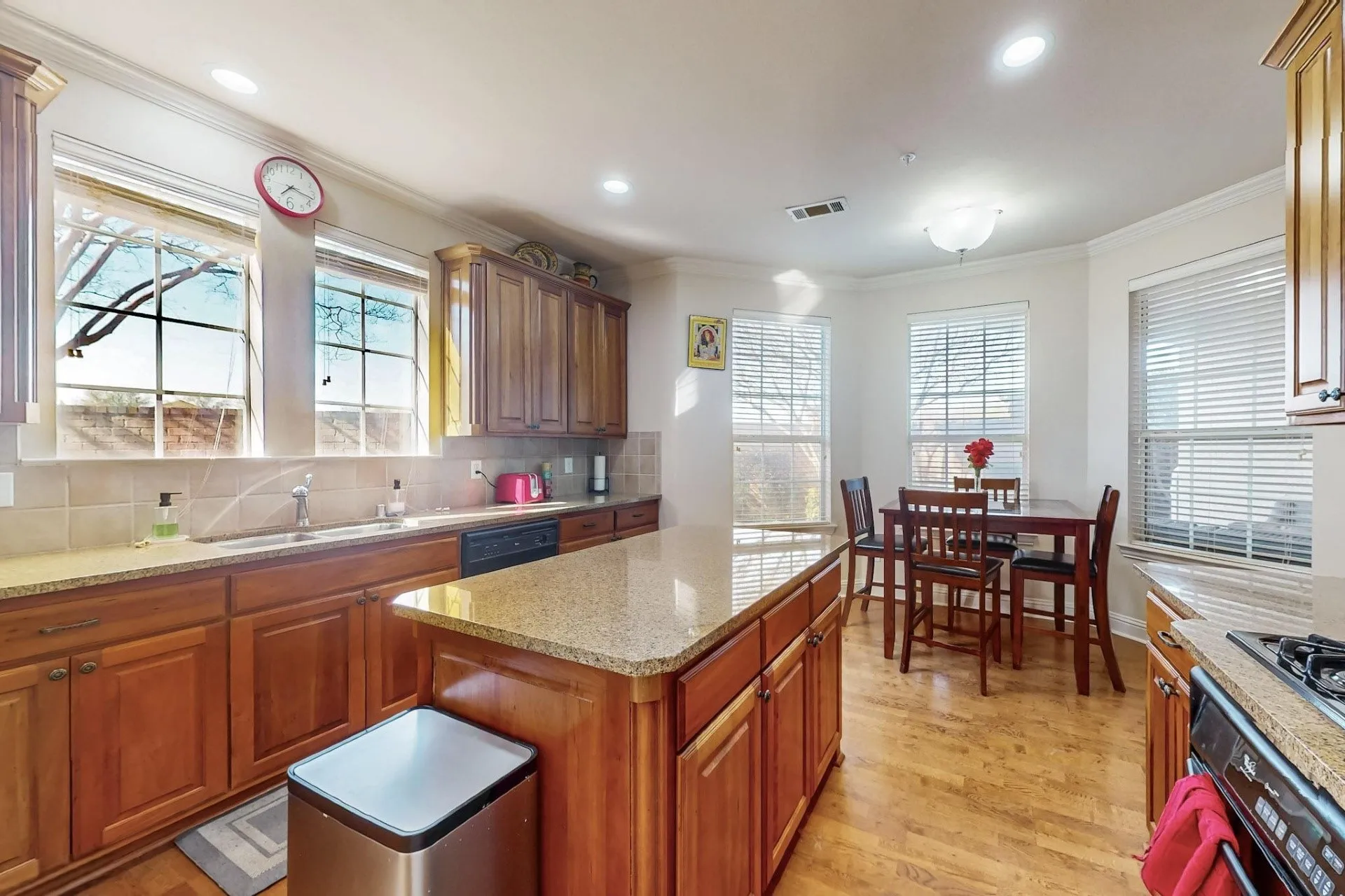 Kitchen featuring stained wood cabinetry, stone countertops, central island, wood-finish flooring, and multiple large windows