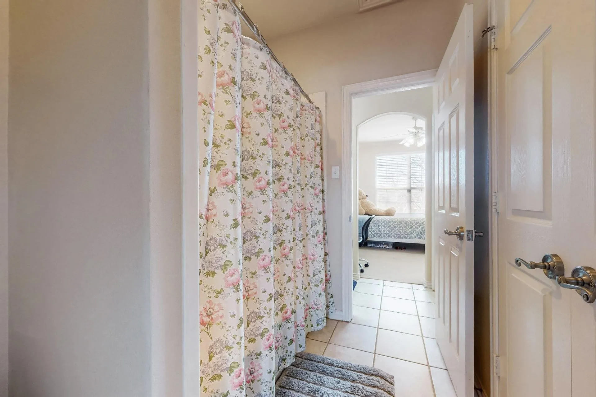 Ceramic tile flooring, six-panel interior doors with metallic lever handles, and a shower alcove