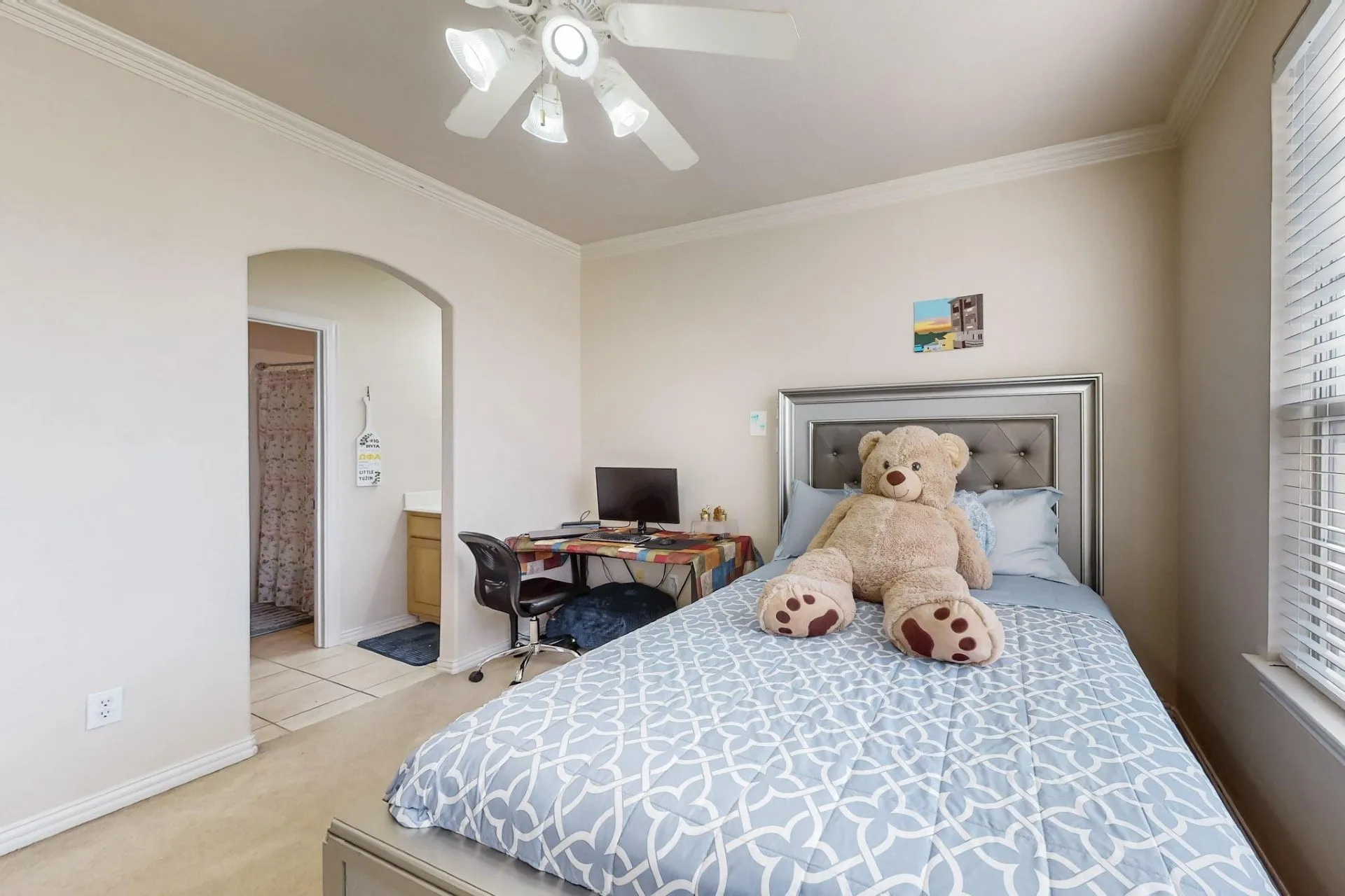Room featuring neutral wall tones, crown molding, a central ceiling fan with multi-light fixture, and an arched entry leading to a tiled area