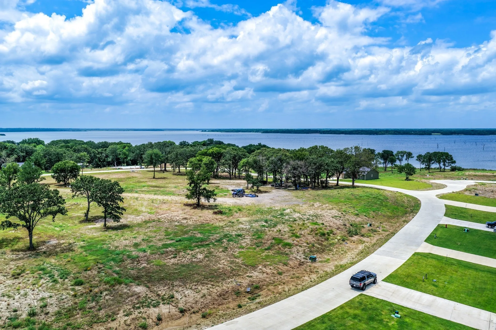 Expansive waterfront lot featuring mature trees, paved access roads, and unobstructed water frontage