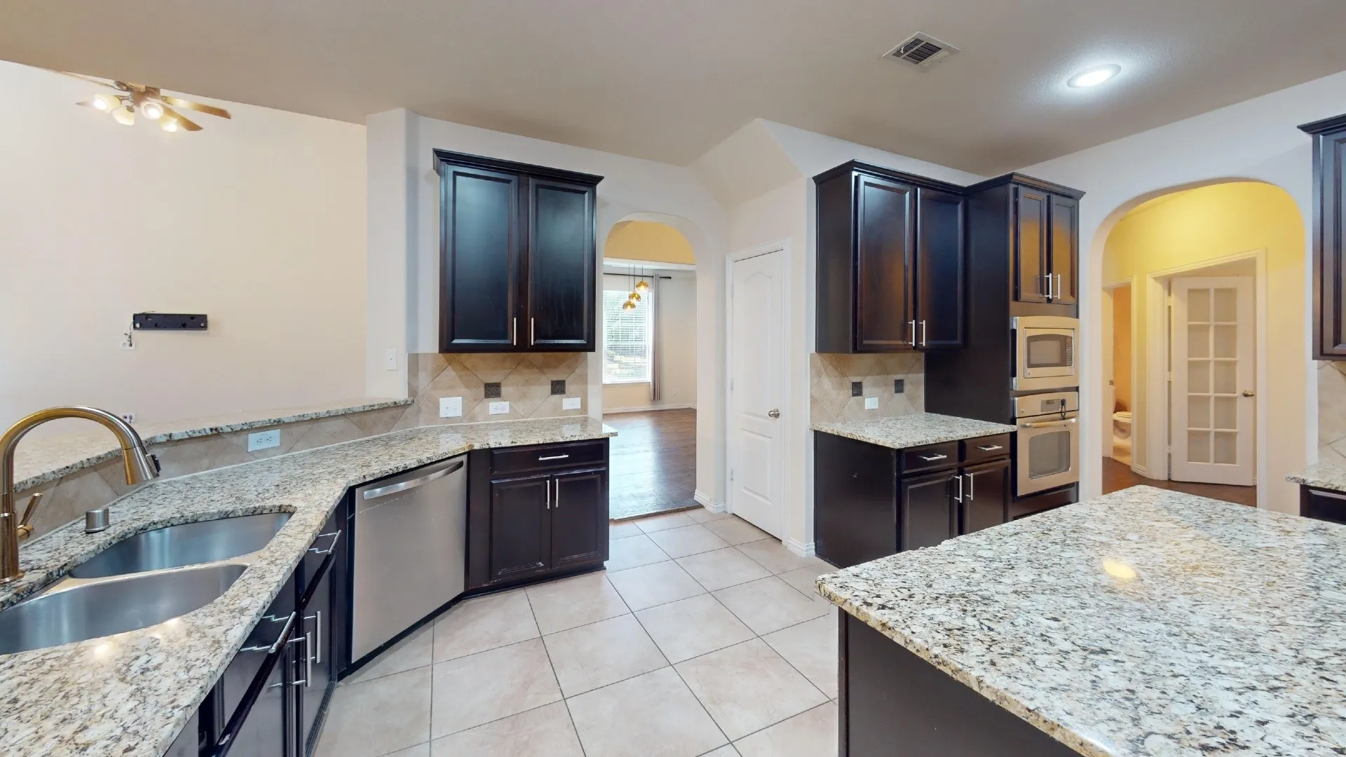 Kitchen featuring dark cabinetry, stone countertops, stainless steel appliances, a center island, and tile flooring