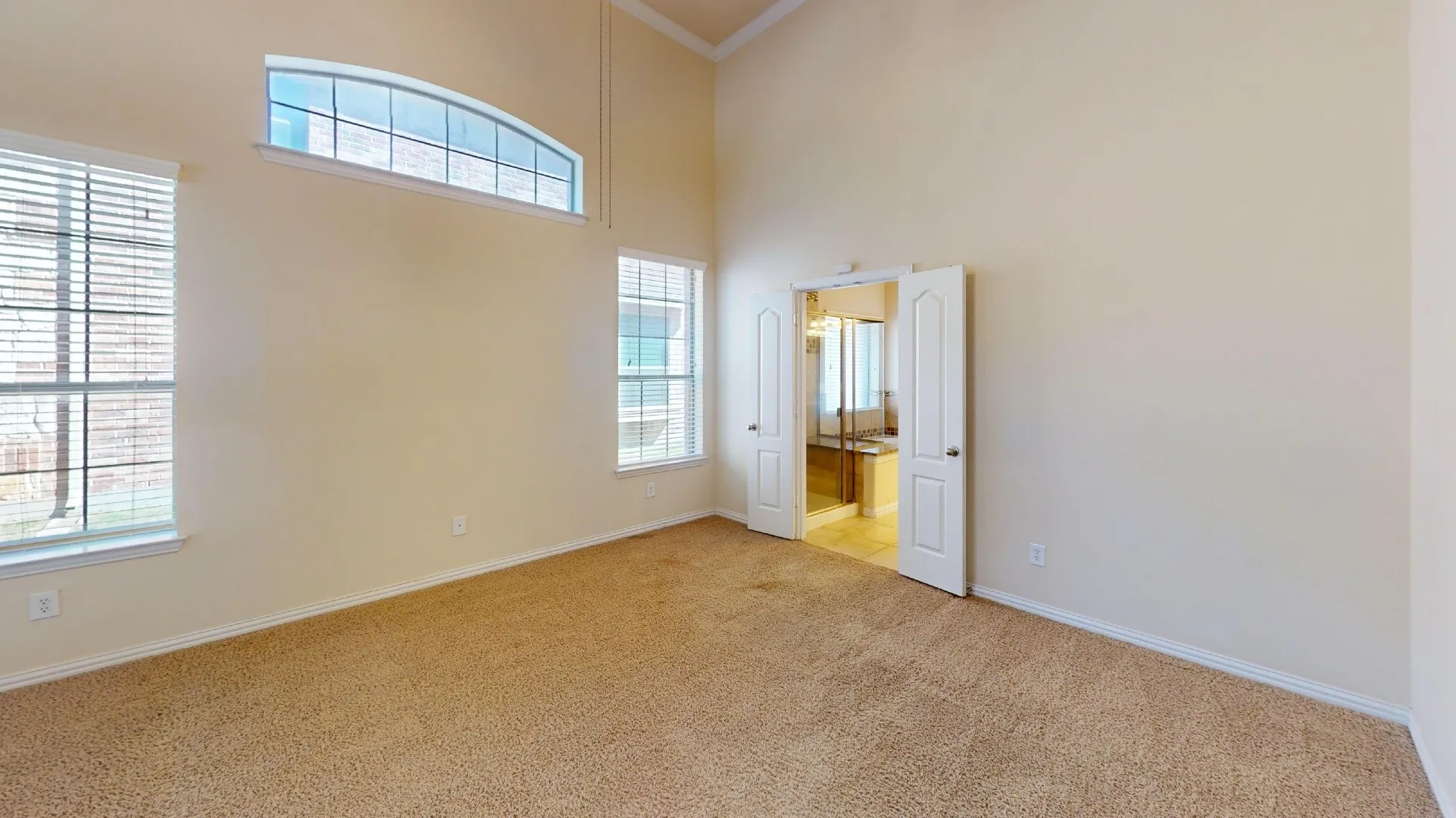 High-ceilinged room featuring wall-to-wall carpeting, an arched transom window, and double-door entry