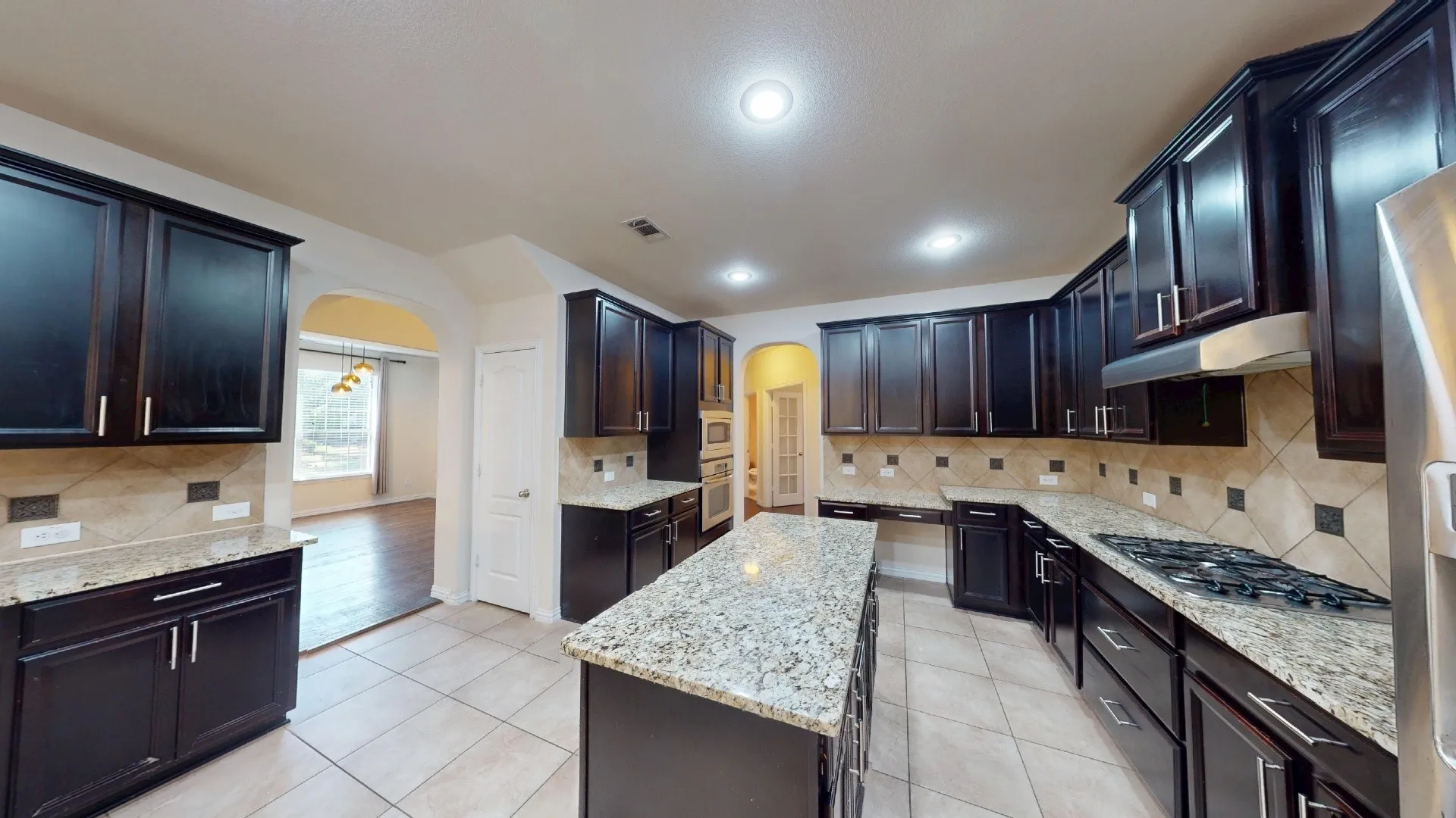 Kitchen featuring dark-finish cabinetry, stone-finish countertops, a central island, recessed lighting, and tile flooring
